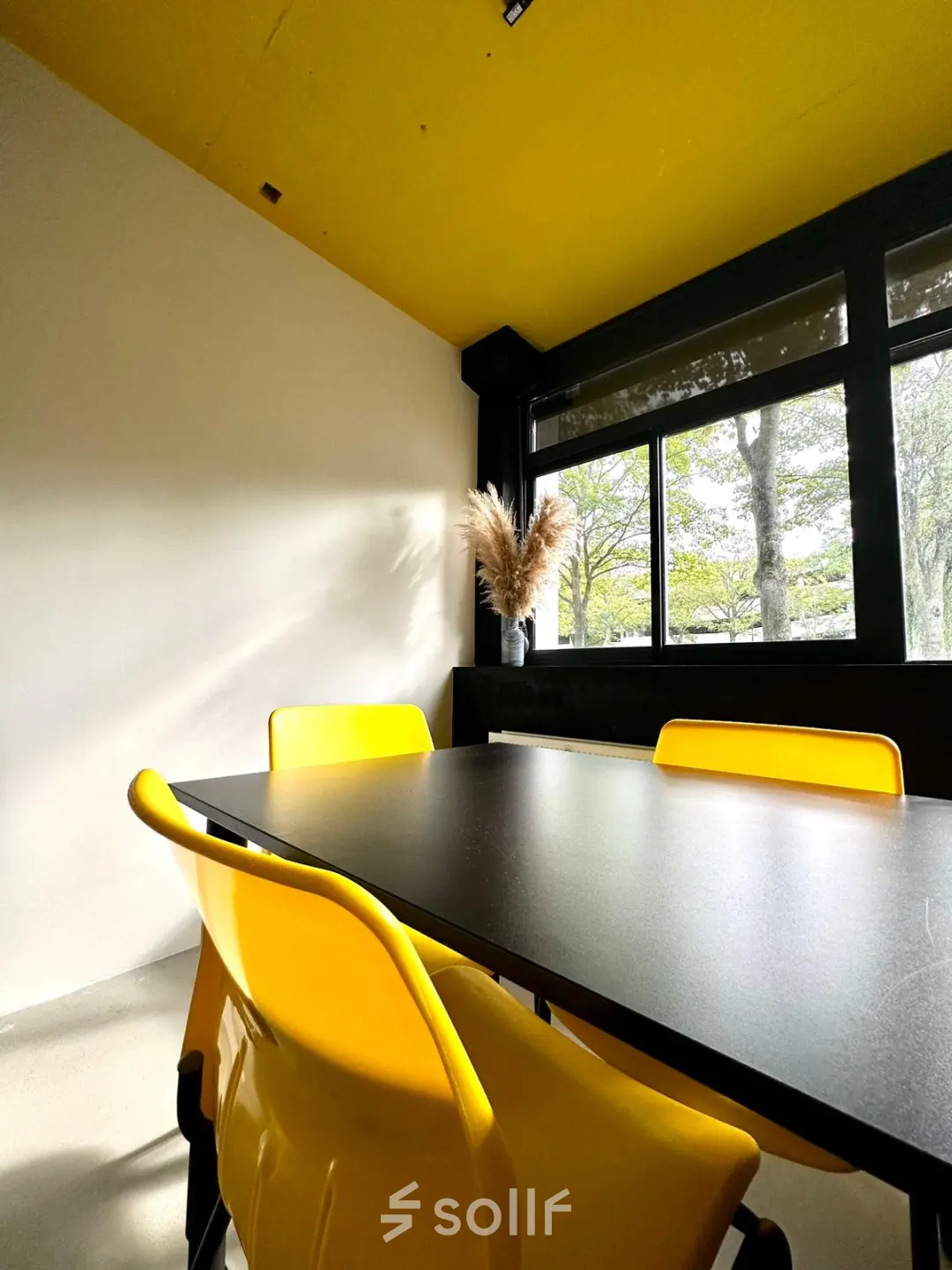 Bright office space at Volmerlaan 7, Rijswijk, featuring a yellow ceiling and chairs around a dark table, available for office space rental.