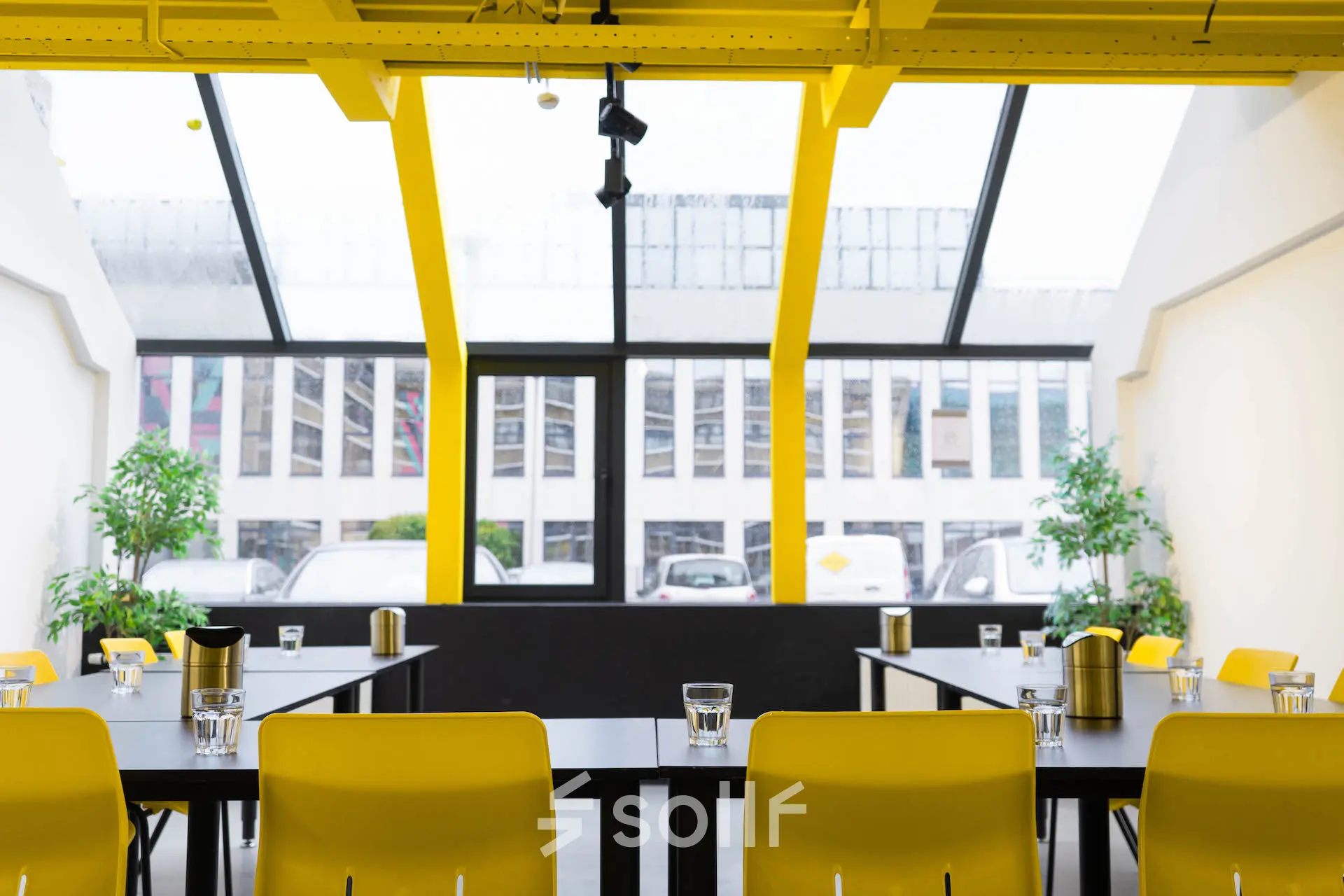 Bright office space at Volmerlaan 7, Rijswijk with large windows, yellow accents, and desks set up for a meeting, available for rent.
