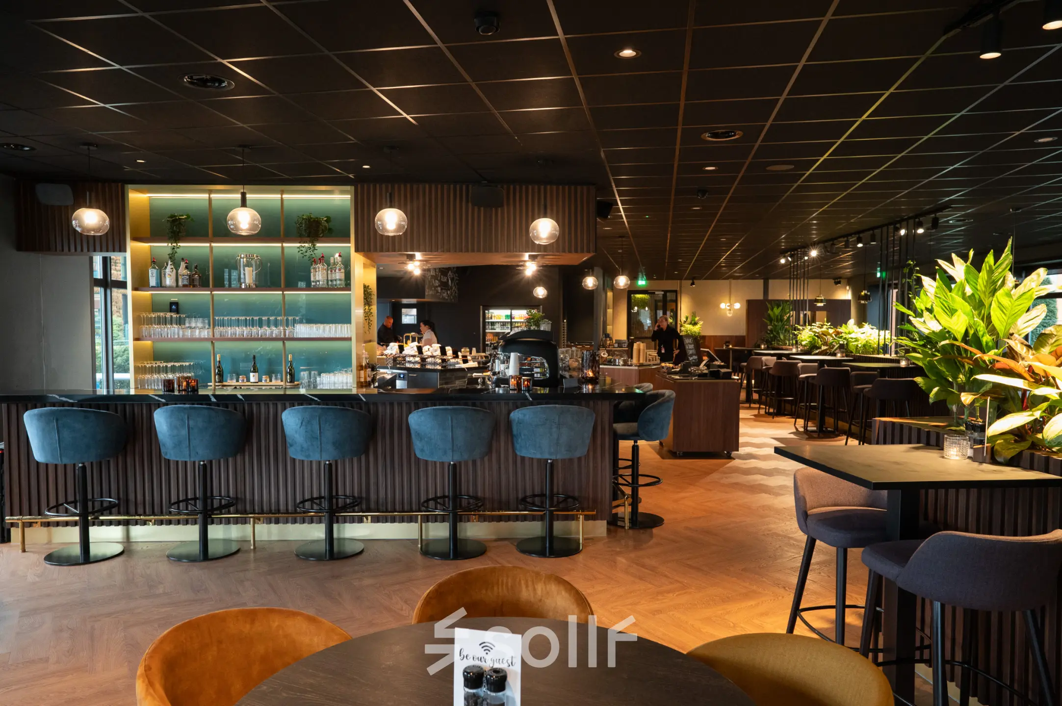 Elegantly furnished office lounge with bar seating and lush green plants at George Hintzenweg 77-89, ideal for rent office space in Rotterdam Alexander.