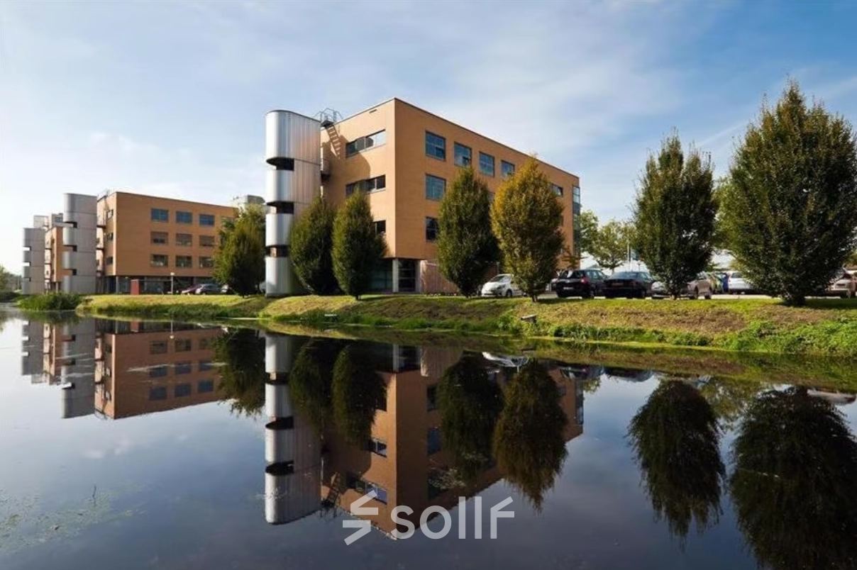 Exterior view of an office building at Hoofdweg 66, Rotterdam Alexander, ideal for office space rental, with a reflective pond and trees.