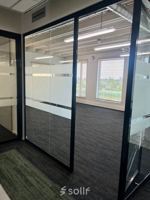Office space available for rent at Bahialaan 100, Rotterdam Brainpark, featuring glass partition walls and carpet flooring with abundant natural light.