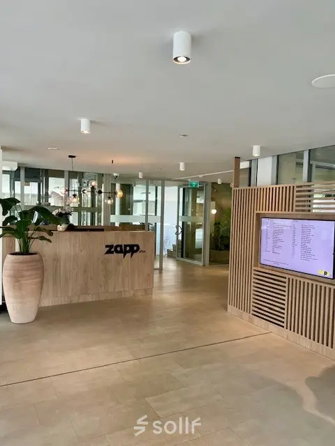Reception area at Bahialaan 100, Rotterdam Brainpark with a modern design, ideal for office space rental featuring a sleek desk and digital display.