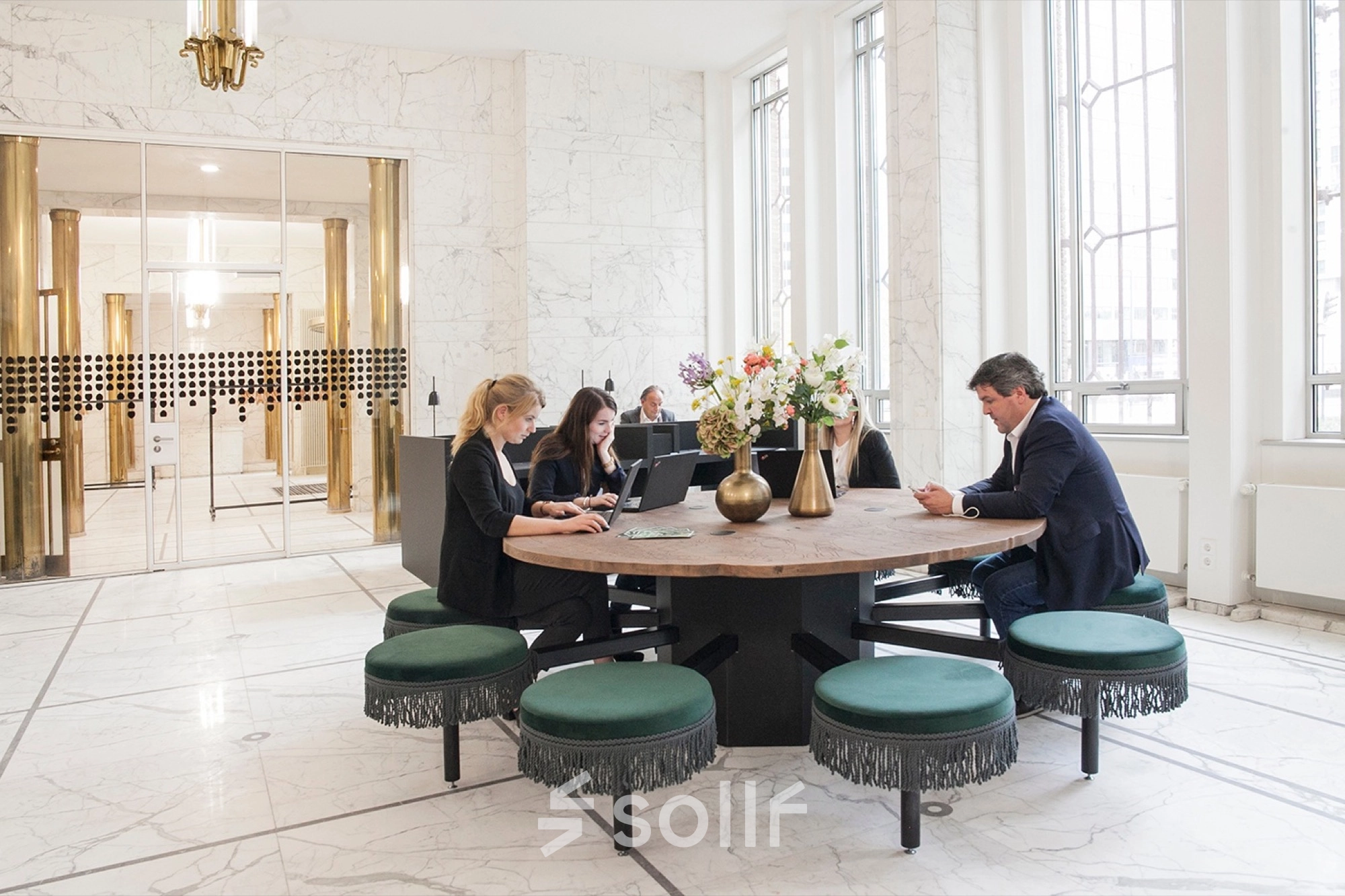 Office space rental at Blaak 34, Rotterdam Center, featuring a round table with people working on laptops.