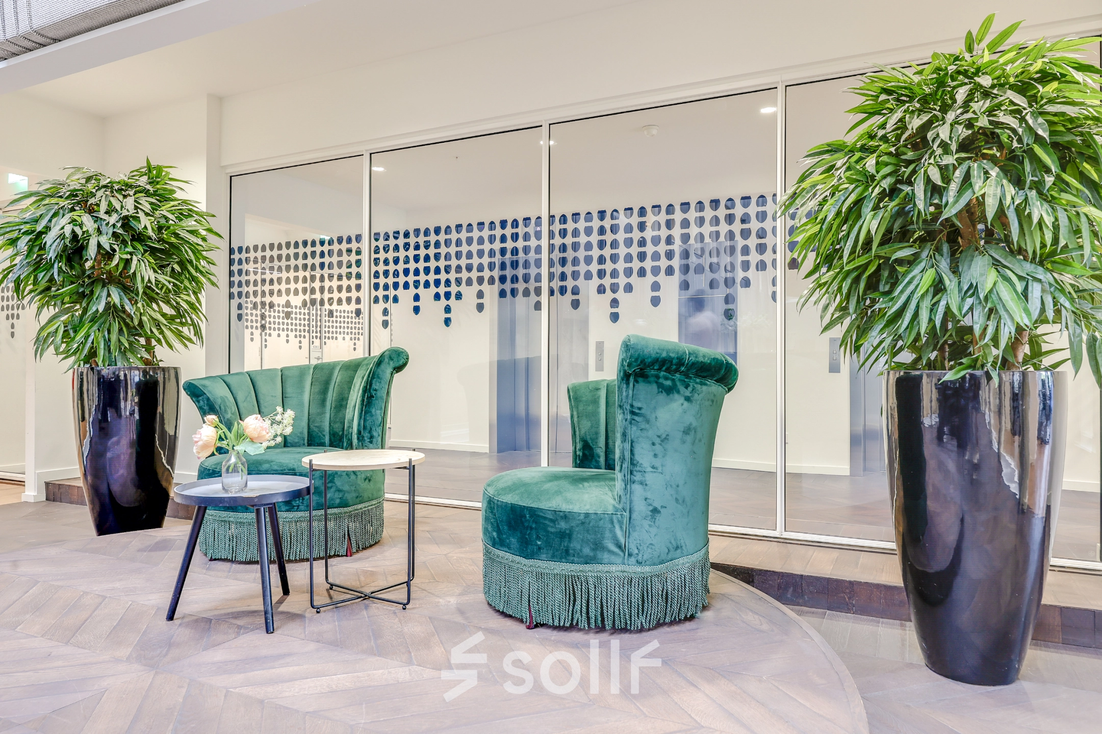 Furnished seating area with green chairs and plants at the office to rent at Blaak 34, Rotterdam Center, ideal for relaxed discussions.