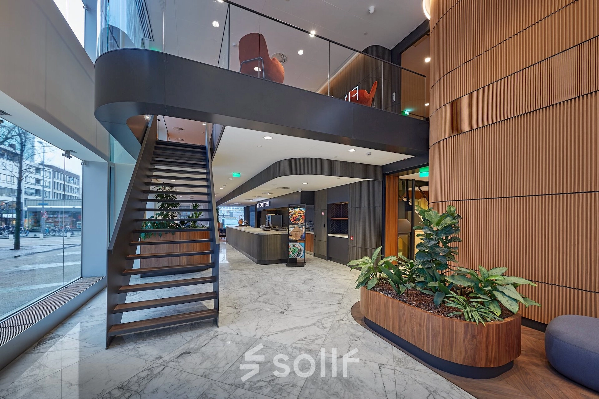 Modern office interior at Blaak 555, Rotterdam Center featuring a sleek staircase, natural lighting, and stylish planter boxes, ideal for office space rental.