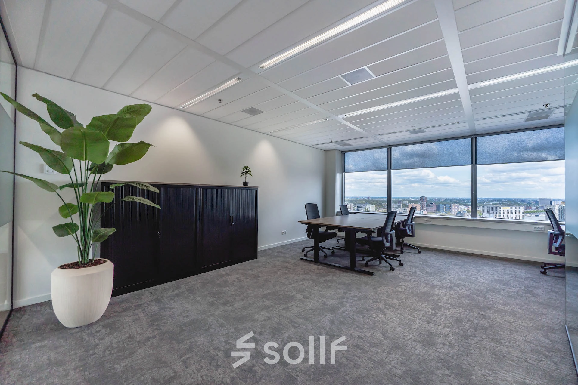 Bright, furnished office space at Blaak 555, Rotterdam Center, featuring large windows, modern furniture, and a city view. Ideal for office space rental.
