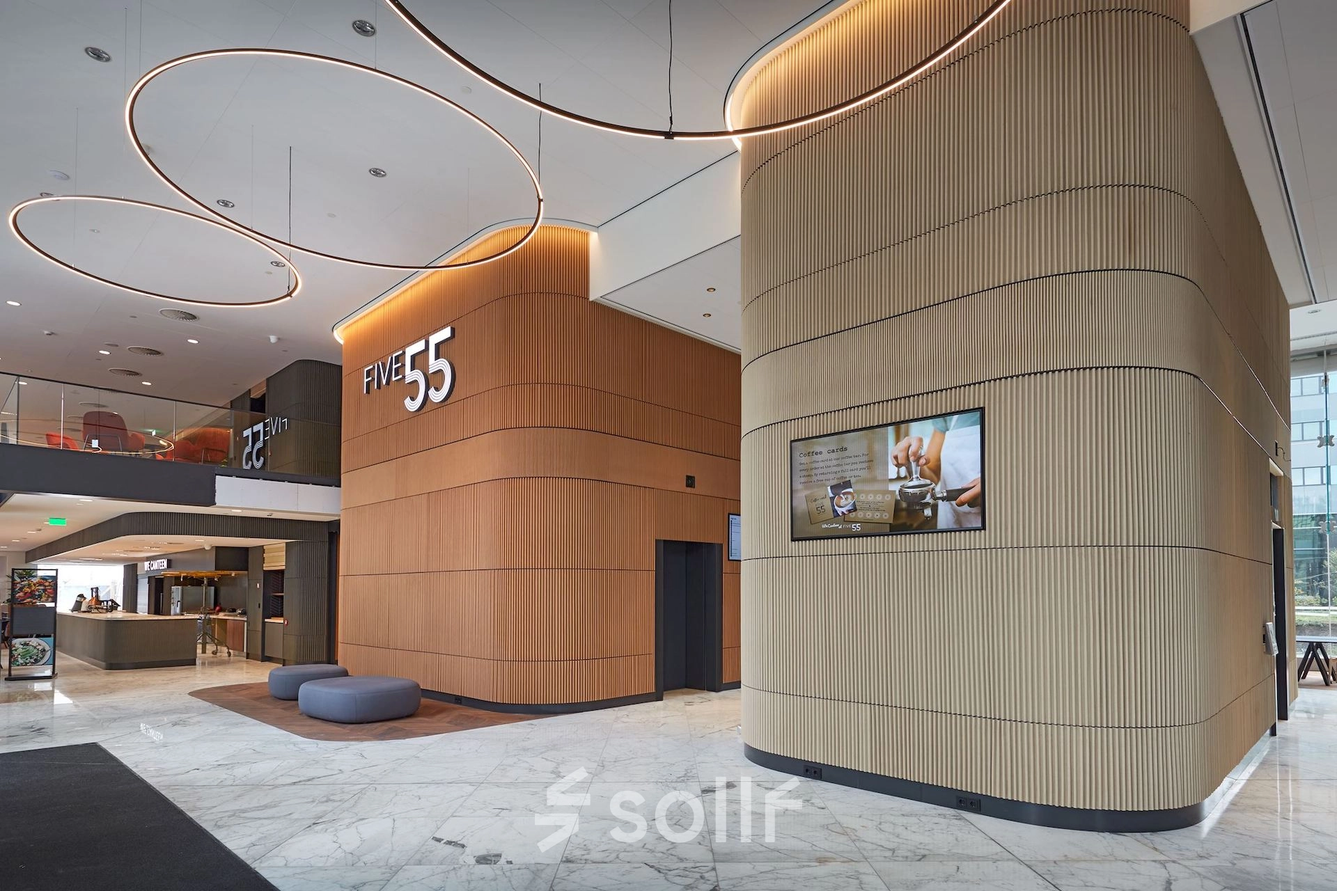 Modern office lobby at Blaak 555, Rotterdam Center with wooden accents and LED lighting, ideal for rent office space.
