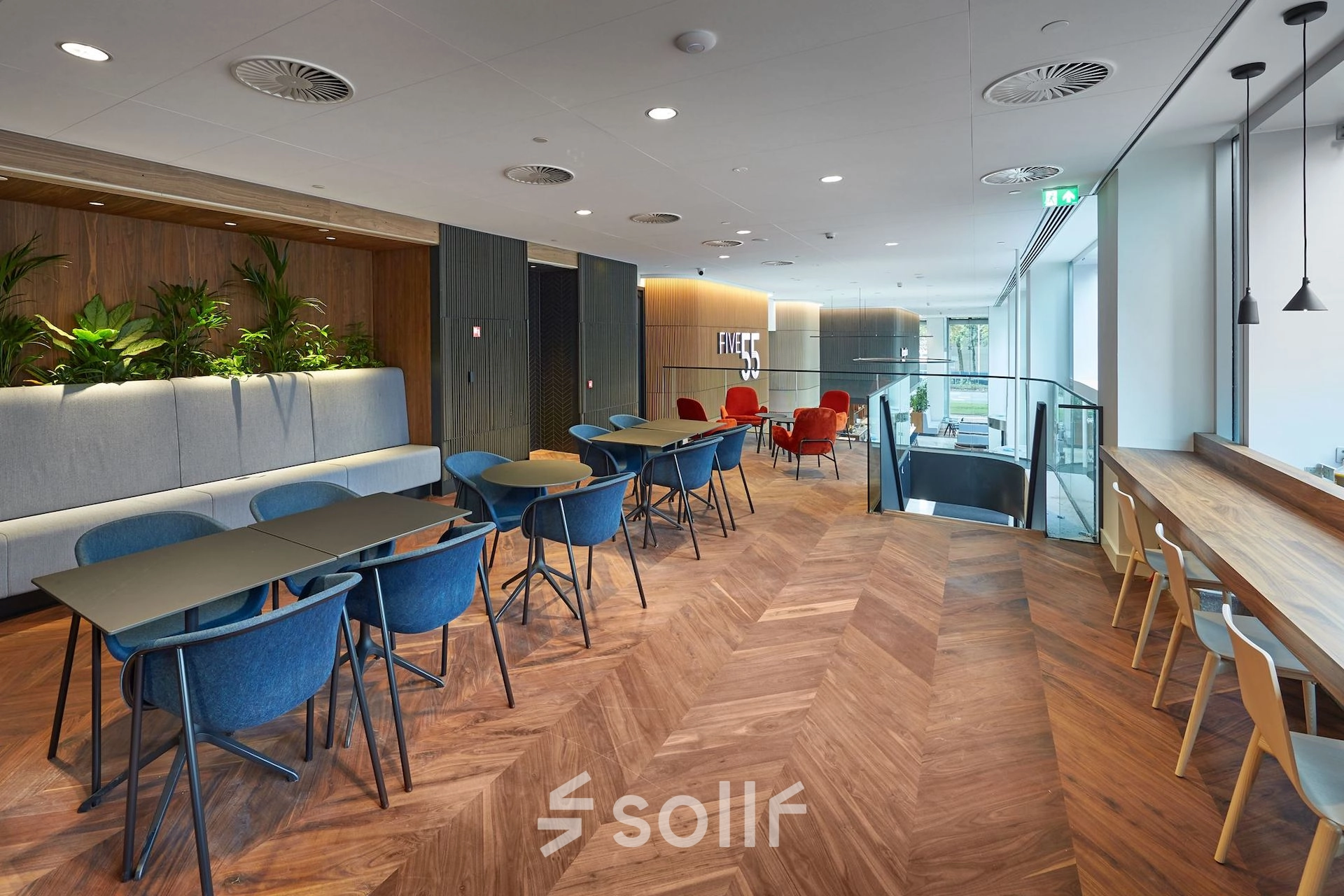 Modern office lounge area at Blaak 555 in Rotterdam Center with stylish decor and ample seating, ideal for office space rental.