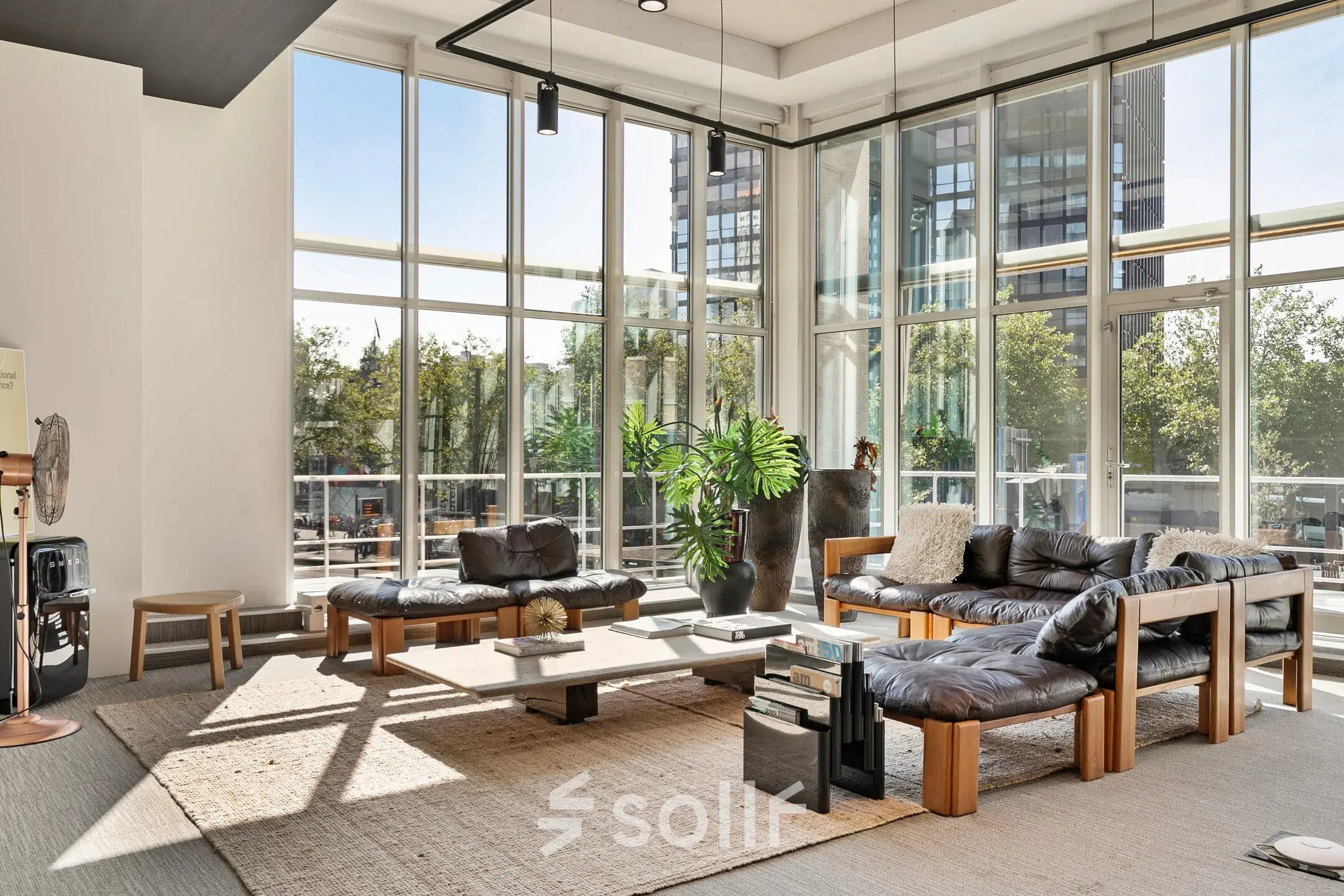 Bright office space at Coolsingel 104 in Rotterdam Center with large windows, modern furniture, and a cozy seating area ideal for meetings. Ideal for office space rental.