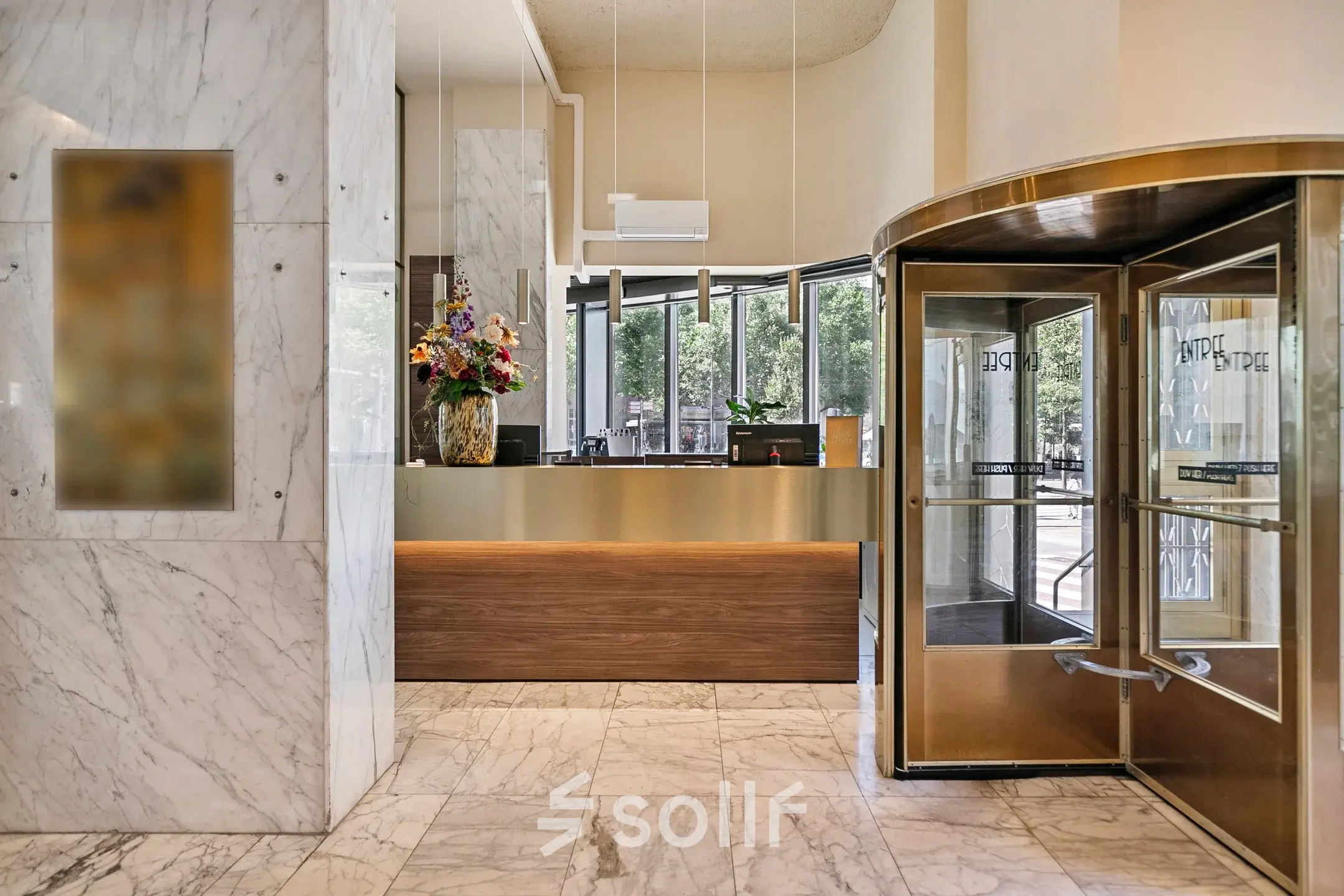 Reception area with marble flooring and a revolving door at the office to rent on Coolsingel 104, Rotterdam Center.