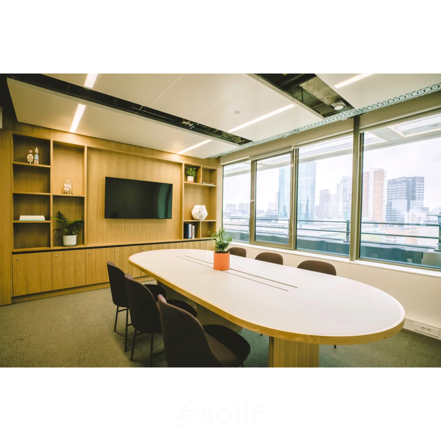 Modern furnished office space at Coolsingel 65, Rotterdam Center, featuring a large table, chairs, shelves, and a window view of the city skyline, ideal for office space rental.