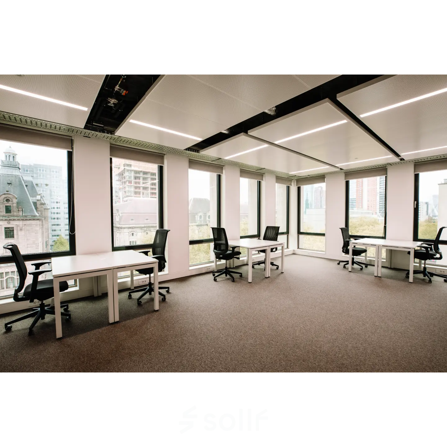 Bright office space with large windows revealing a city view, featuring several black chairs and white desks at Coolsingel 65, ideal for those seeking office space rental in Rotterdam Center.