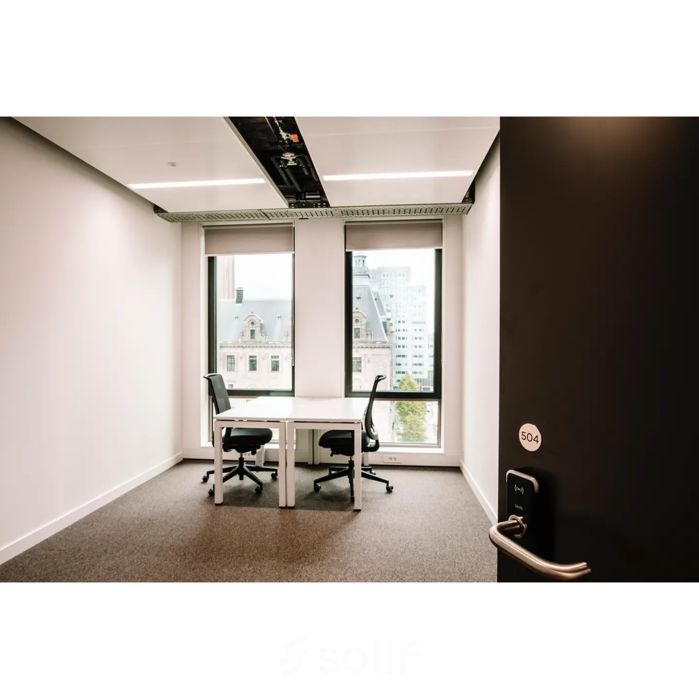 A modern furnished office at Coolsingel 65, Rotterdam Center, featuring two desks and large windows offering a city view, ideal for office space rental.