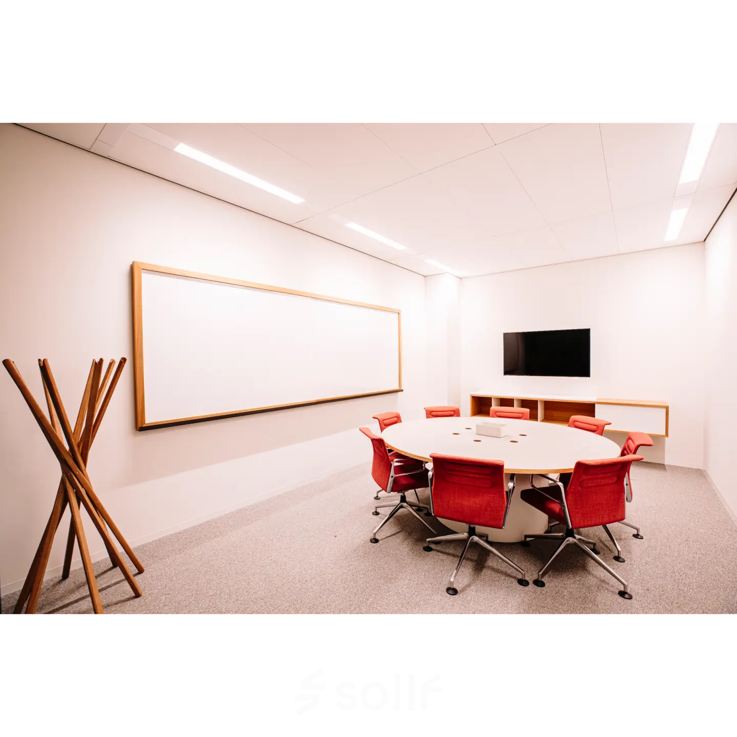 Conference room at Hoogstraat 185 in Rotterdam Center, featuring a round table with red chairs, a wall-mounted screen, and a whiteboard. Ideal office space rental option.
