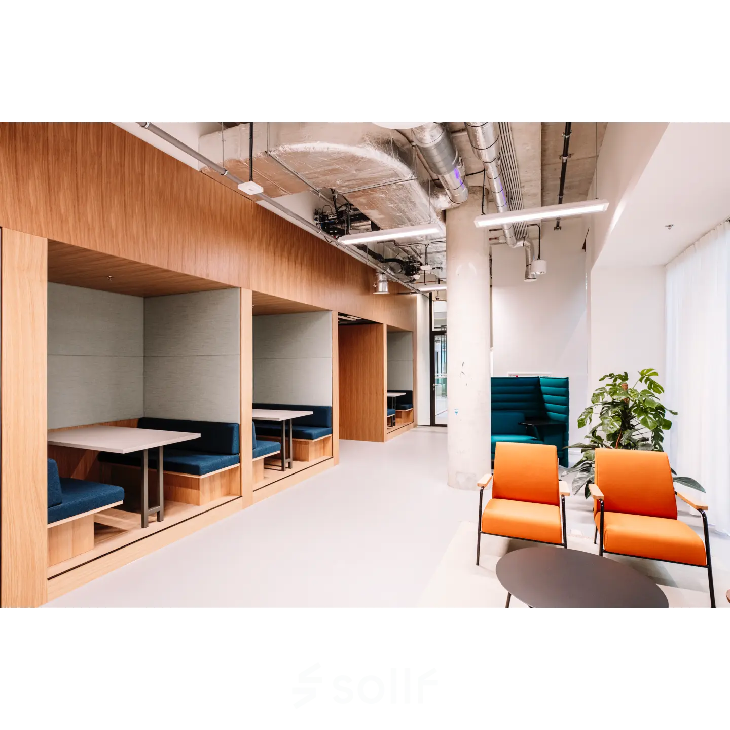 Modern office space in Rotterdam Center with stylish wooden booths and colorful seating, perfect for collaboration or meetings. Ideal for office space rental in a vibrant location.