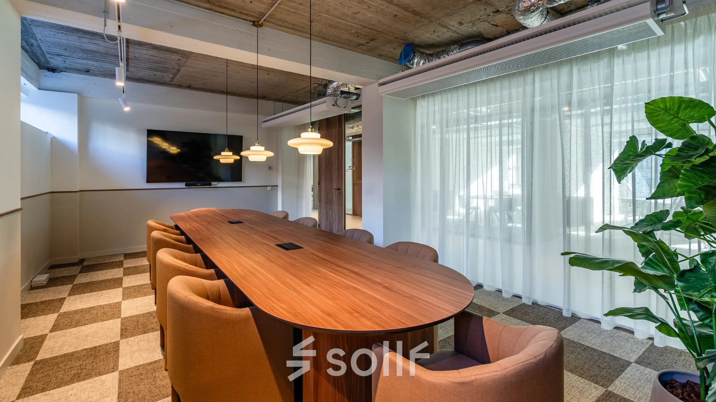 Modern conference room with a long wooden table, cushioned chairs, and a mounted TV at the office space rental in Rotterdam Center.