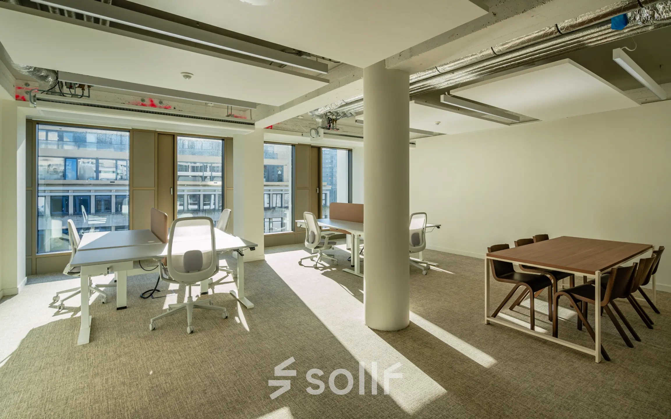 Bright office space with modern furniture and large windows at Stadhuisplein 9-23, Rotterdam Center for rent. Several desks and chairs arranged for business activities, ideal for office space rental.