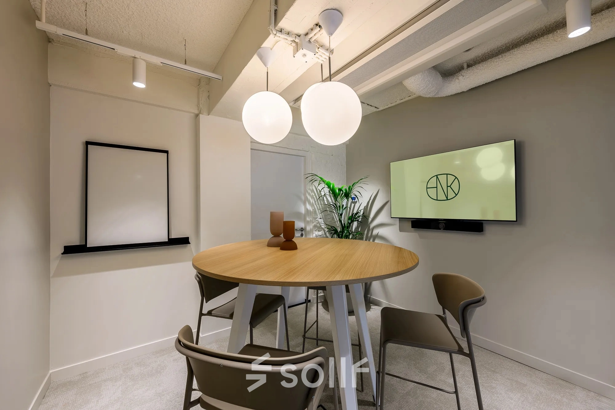 Modern conference room at Vasteland 42-110 in Rotterdam Center with a round table, chairs, and a wall-mounted screen, suitable for office space rental.