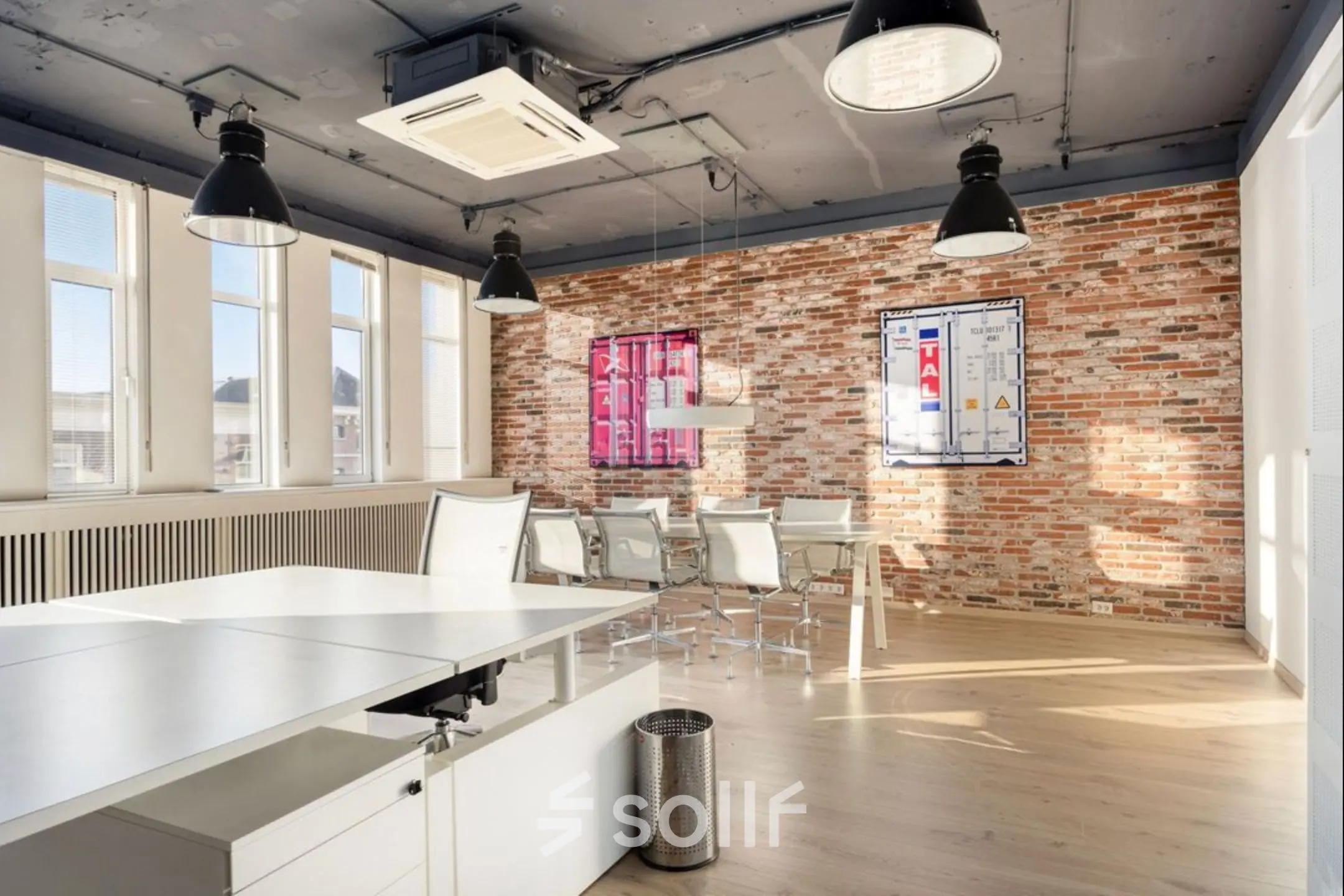Spacious office space at Veerhaven 7, Rotterdam Center, featuring exposed brick walls, ample natural light, and modern furnishings. Ideal for office space rental with a mix of desks and a meeting area.