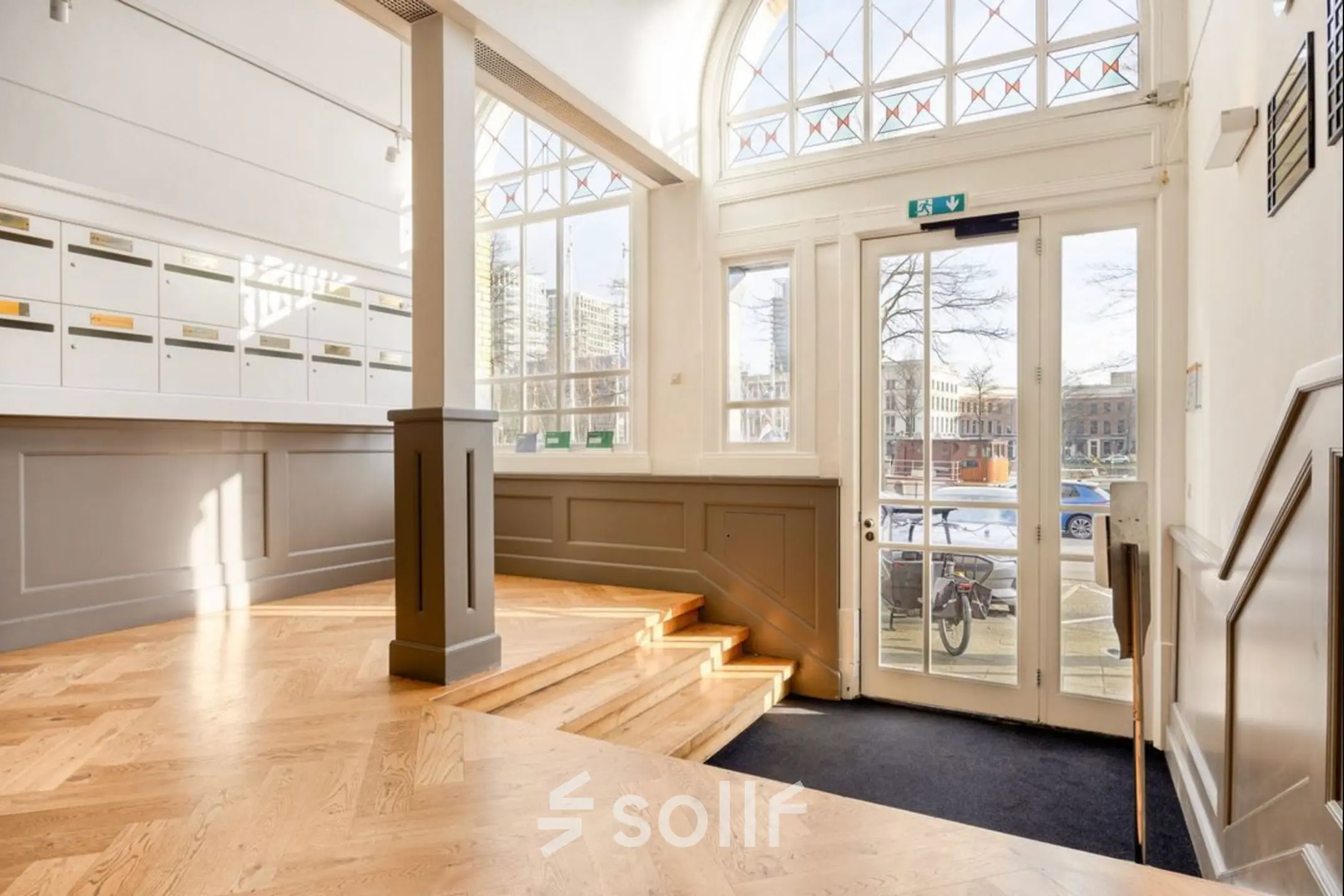 Bright entrance area of office space rental at Veerhaven 7, Rotterdam Center, featuring wooden flooring and tall windows letting in natural light.