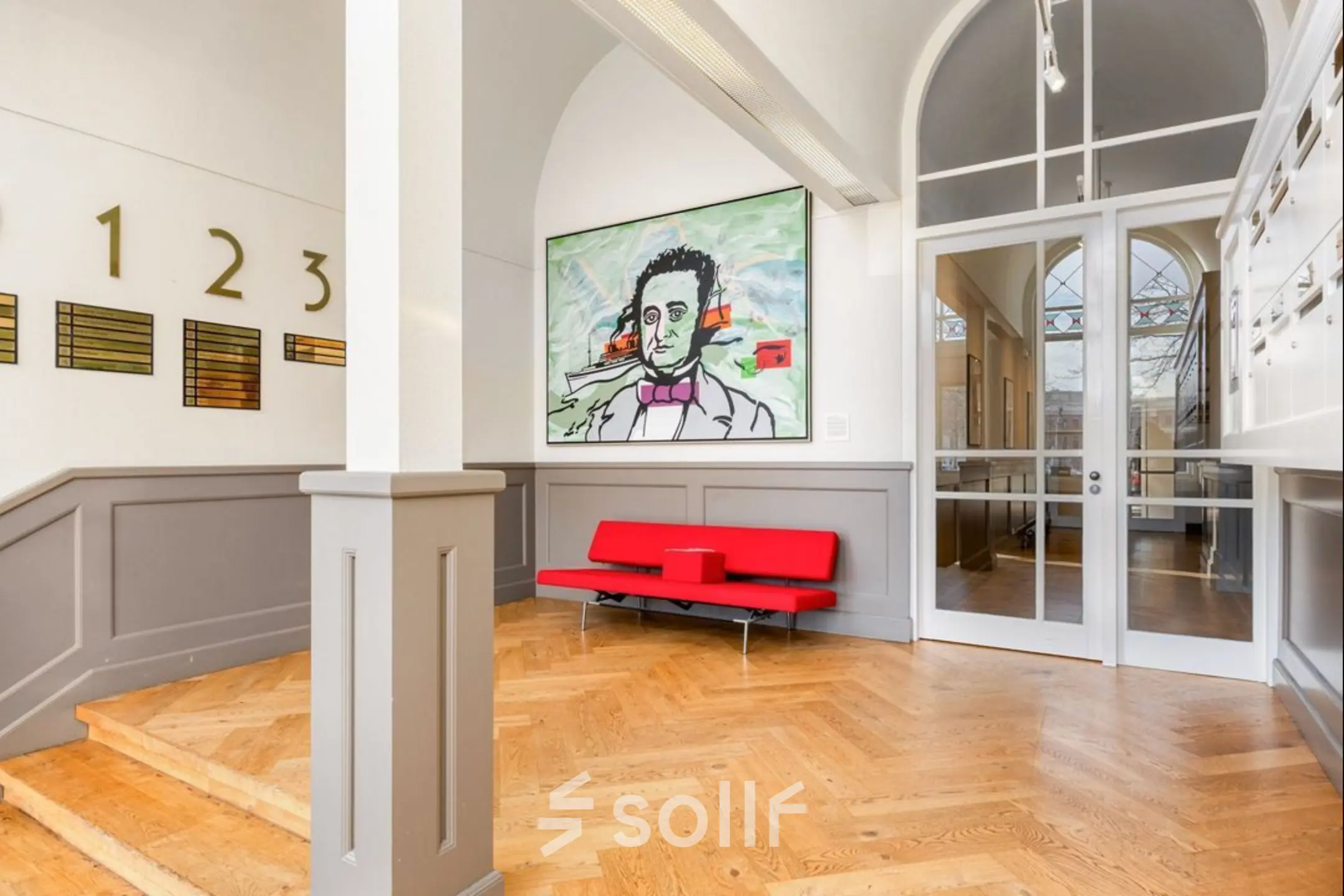 A stylish reception area at Veerhaven 7, Rotterdam Center, featuring parquet flooring, a vibrant painting, and a sleek red bench. Ideal space to rent as office or for office space rental.
