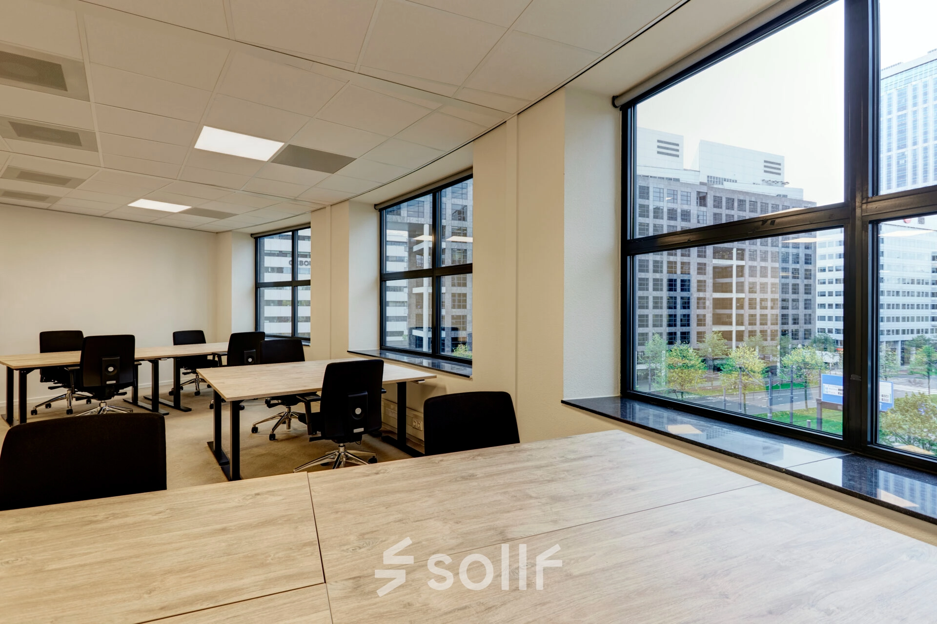 Spacious office space rental with large windows in Rotterdam Center, featuring wooden desks and rolling chairs, ideal for those looking to rent office space at Weena 335.