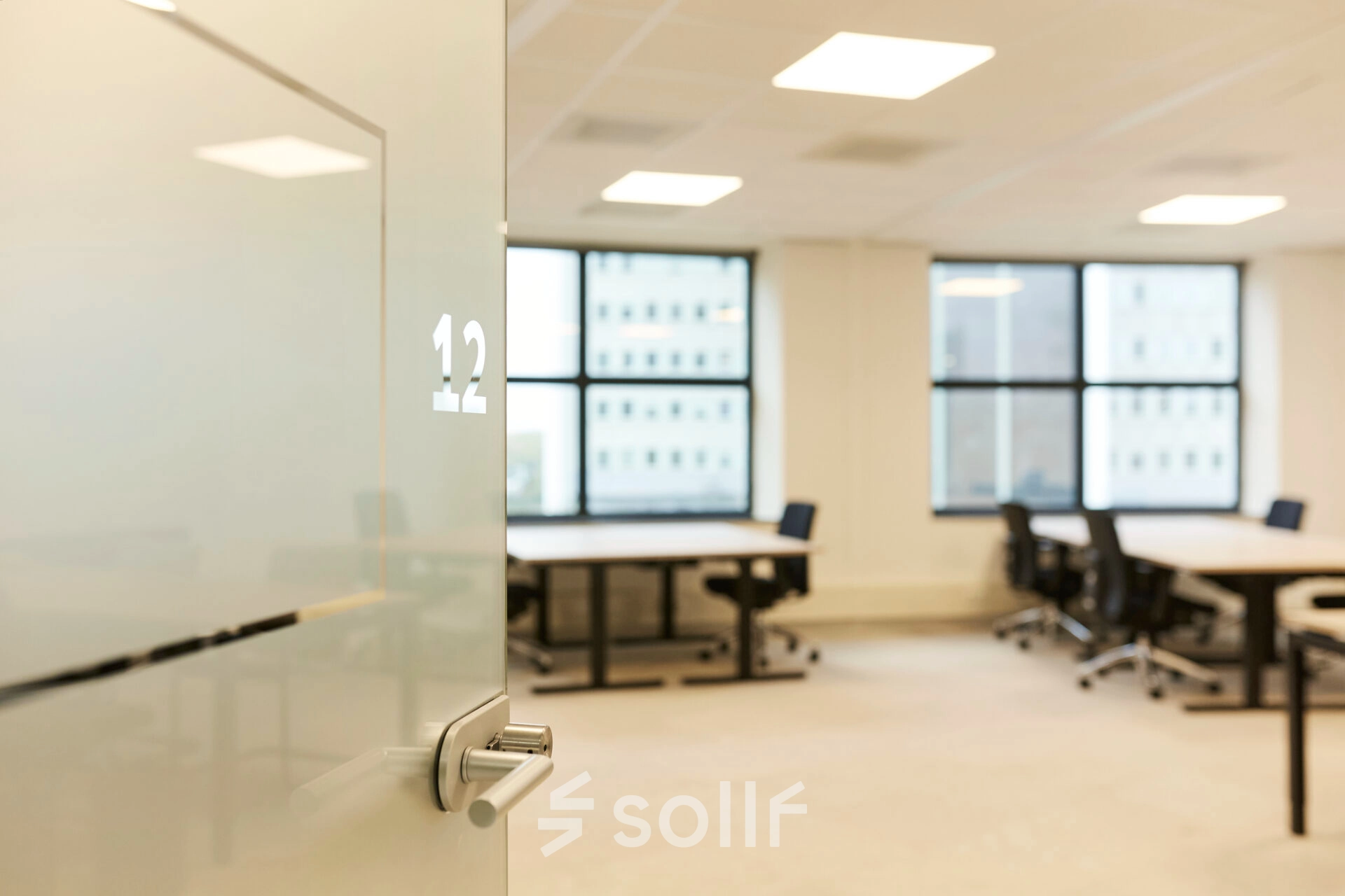 Bright office space for rent at Weena 335, Rotterdam Center, featuring desks, chairs, and large windows that offer natural light, ideal for productive work.