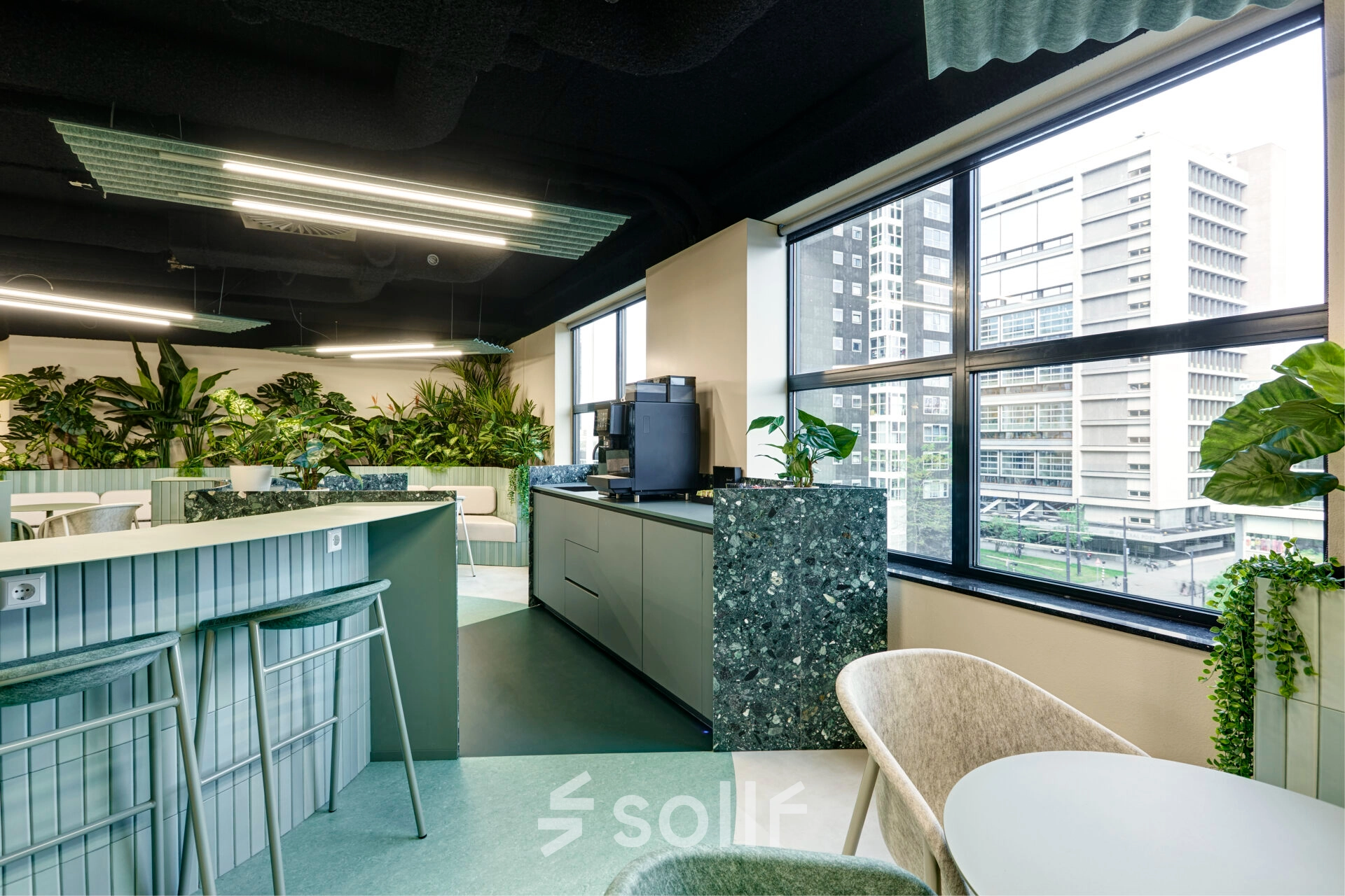 Stylish office space with modern furnishings and lush plants, offering a view of Rotterdam Center. Ideal for office space rental at Weena 335.