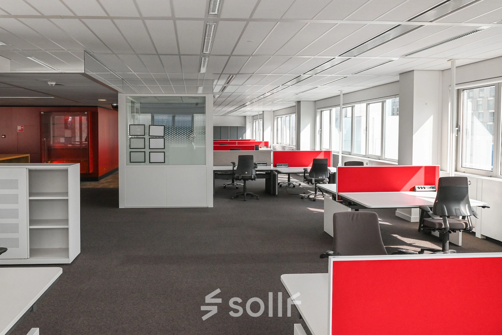 Bright office space rental at Weena 70, Rotterdam Center, featuring modern workstations with red dividers and ample natural light, ideal for businesses seeking an office to rent.