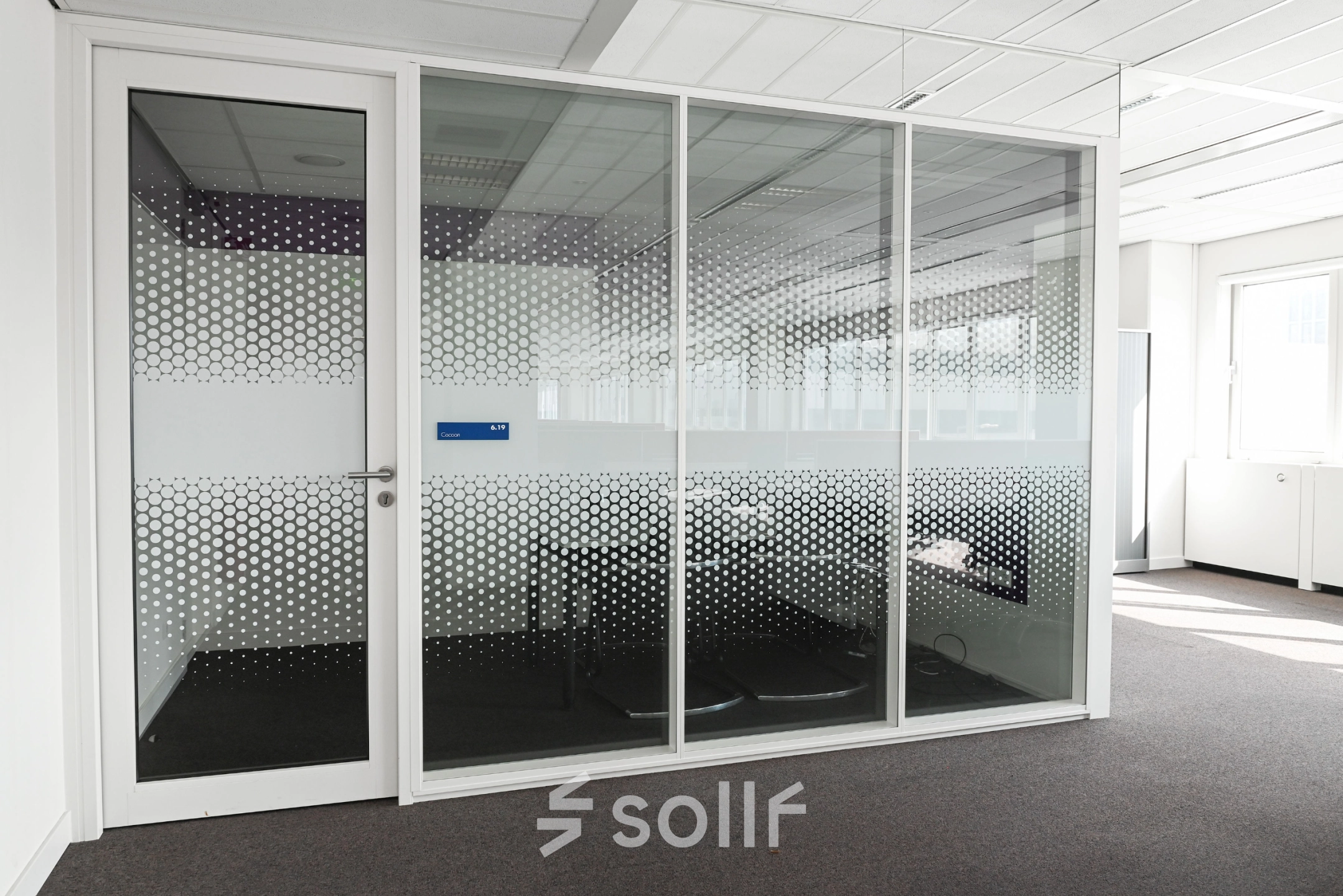 Modern office space to rent at Weena 70, Rotterdam Center, featuring a glass-walled meeting room with geometric patterns offering natural light.