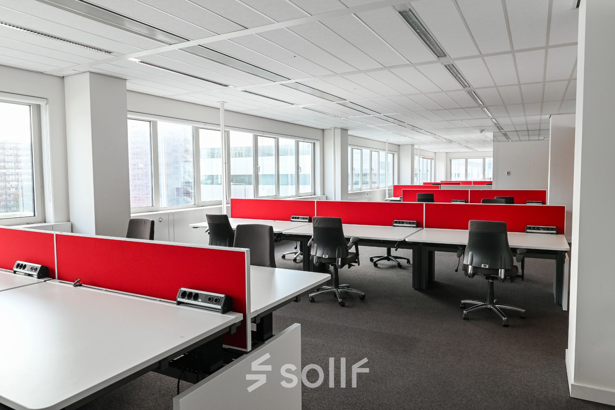 Bright office space for rent at Weena 70, Rotterdam Center, featuring rows of desks with red dividers and rolling chairs, ideal for office space rental.