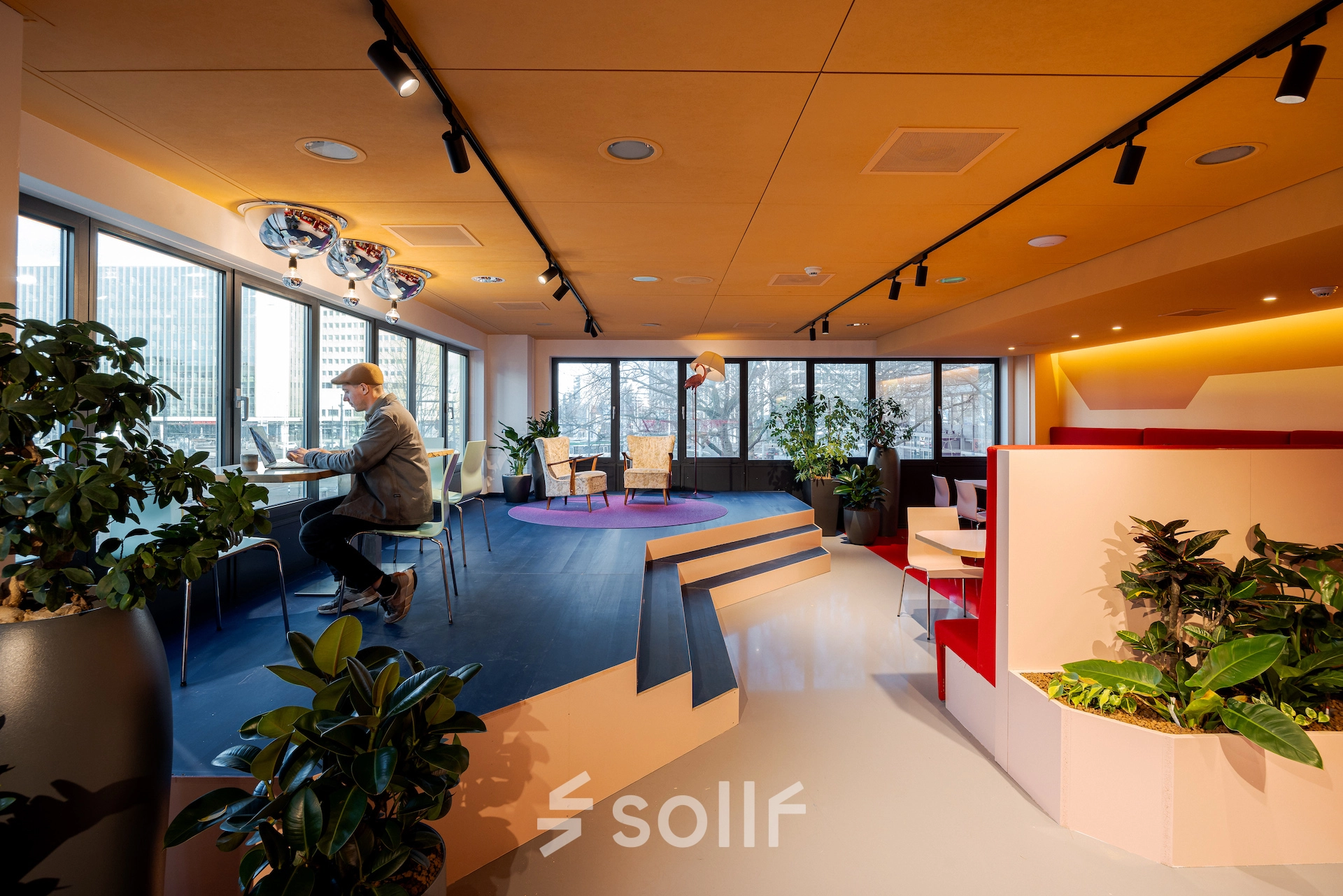 Bright office space at Weena 70 in Rotterdam Center, featuring modern furnishings, large windows and a professional working area with an individual at a desk. Ideal for office space rental.