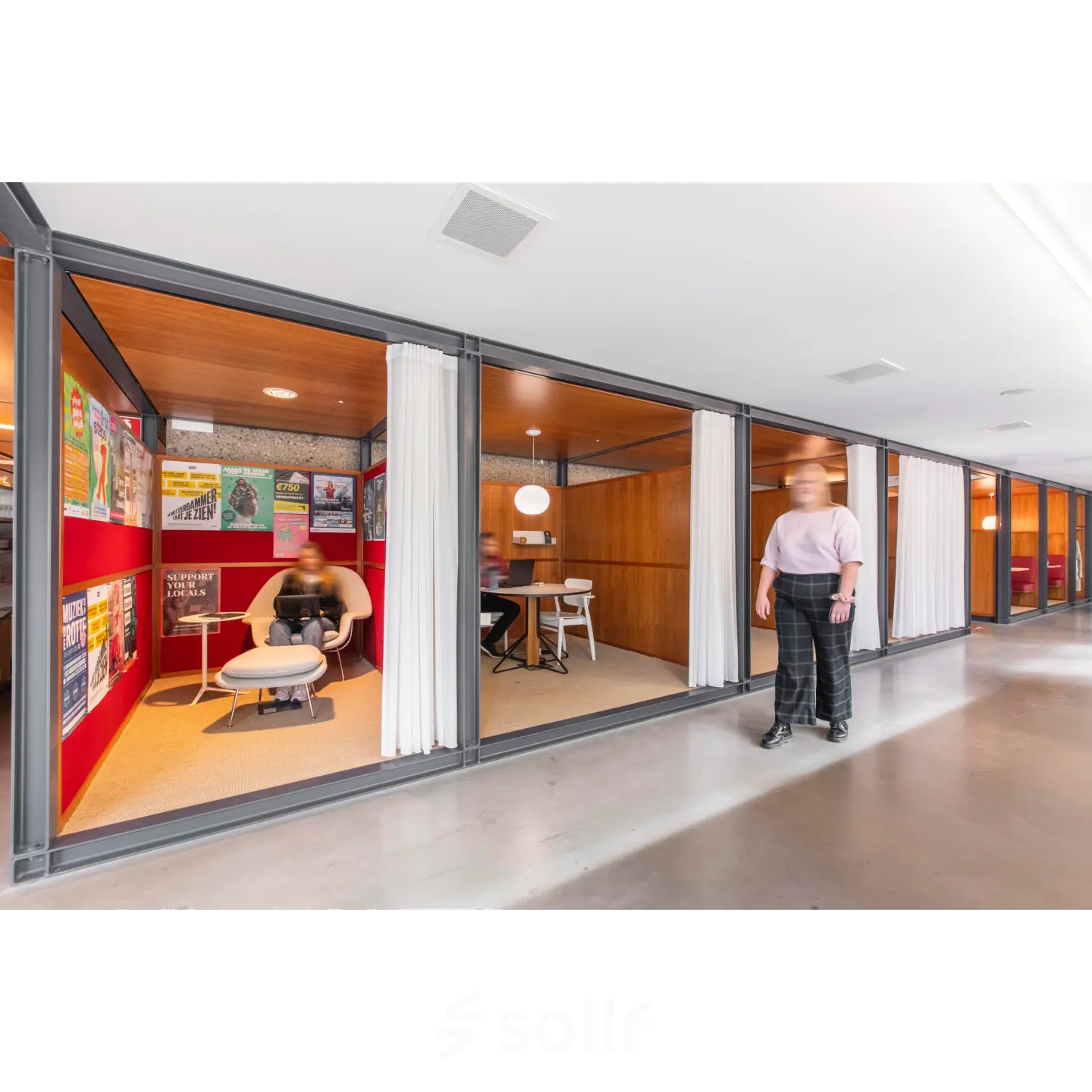 Interior view of office space at Hofplein 20, Rotterdam Central Station, with furnished meeting areas and a person talking and another seated. Ideal for office space rental.