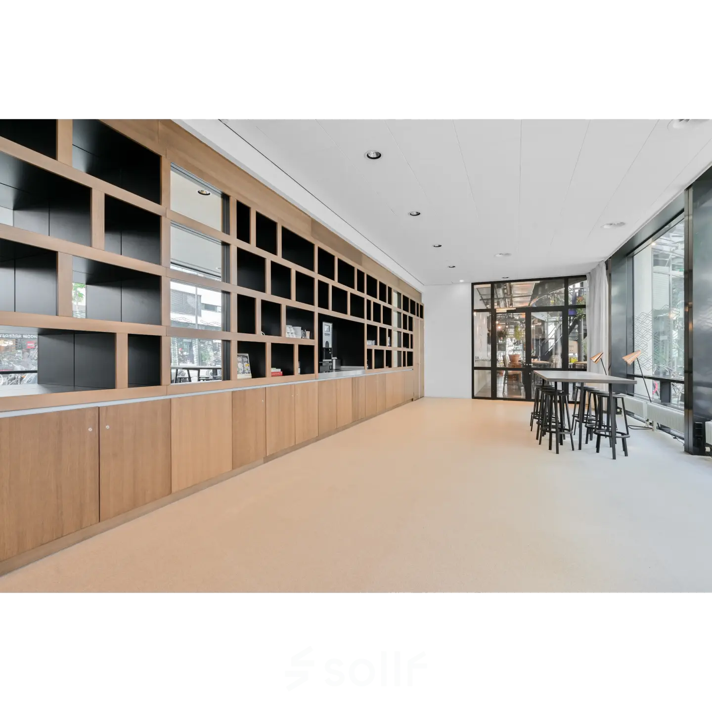 Spacious furnished office available for rent at Weena 290, Rotterdam Central Station, featuring modern interiors with wooden shelving and large windows offering natural light.