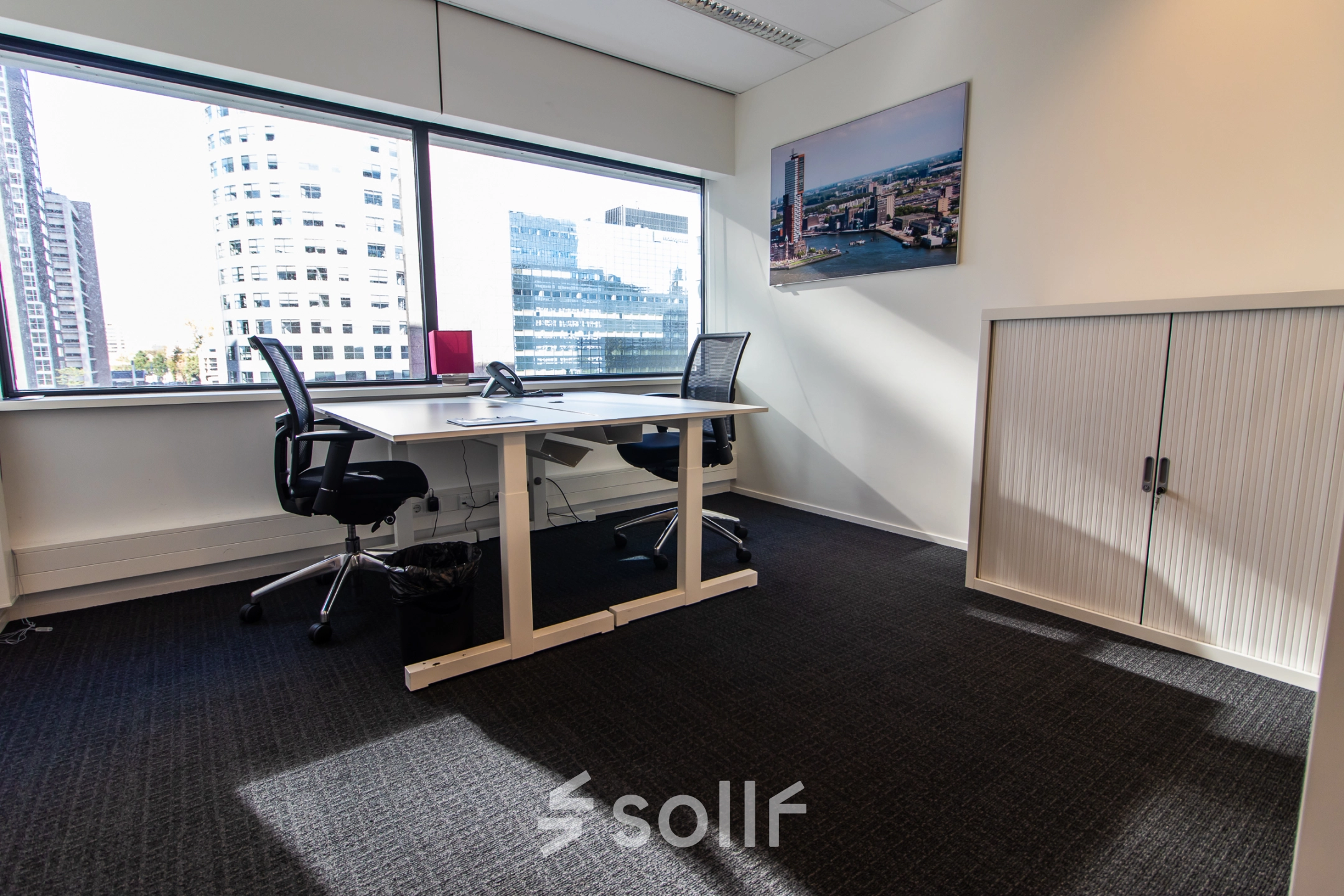 Bright office space at Weena-Zuid 130, Rotterdam Central Station, featuring two desks with black chairs, large window views, and minimalist decor. Ideal for office space rental.