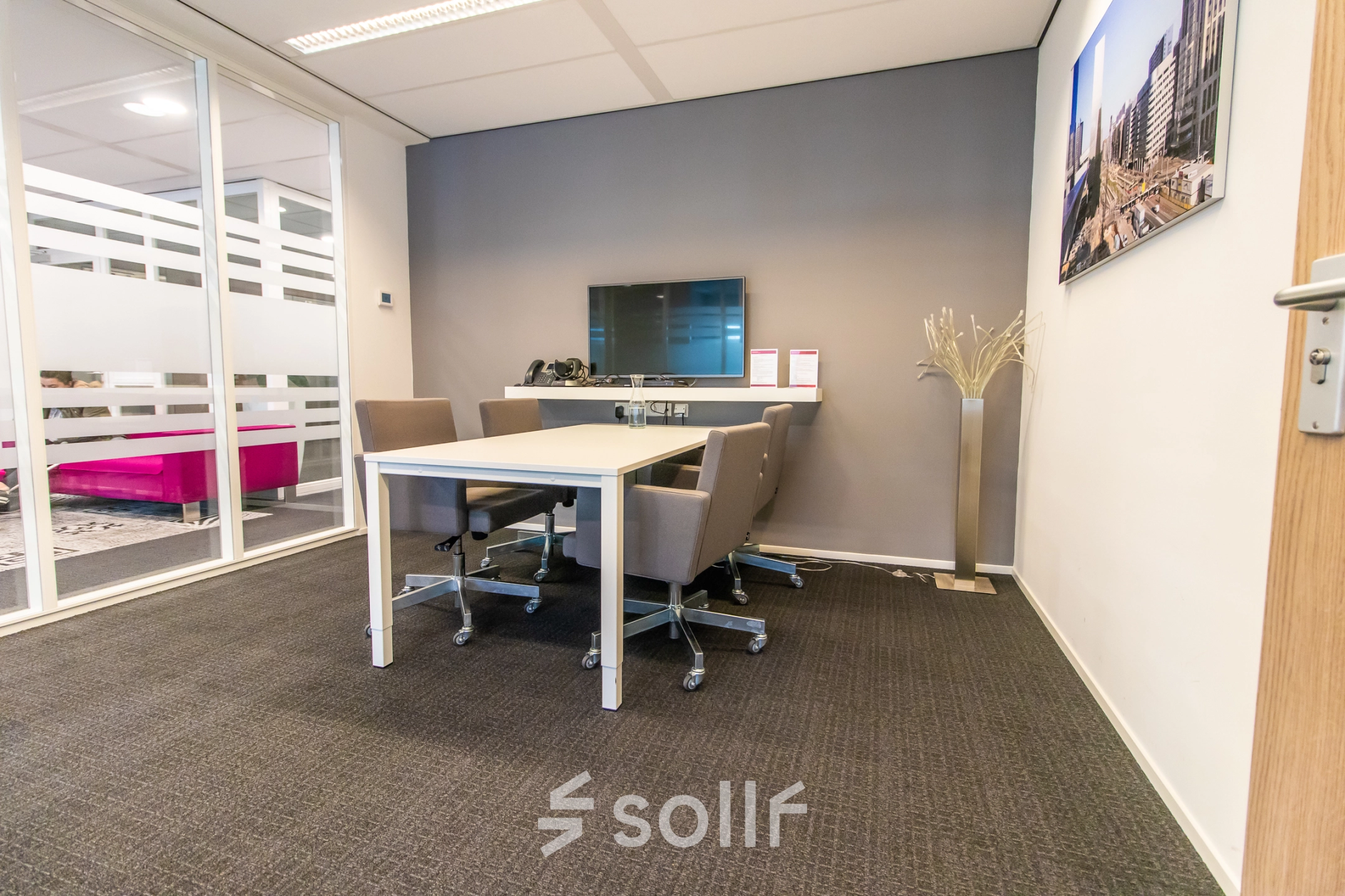Furnished office space rental at Weena-Zuid 130, Rotterdam Central Station with meeting table, chairs, screen, and modern decor.