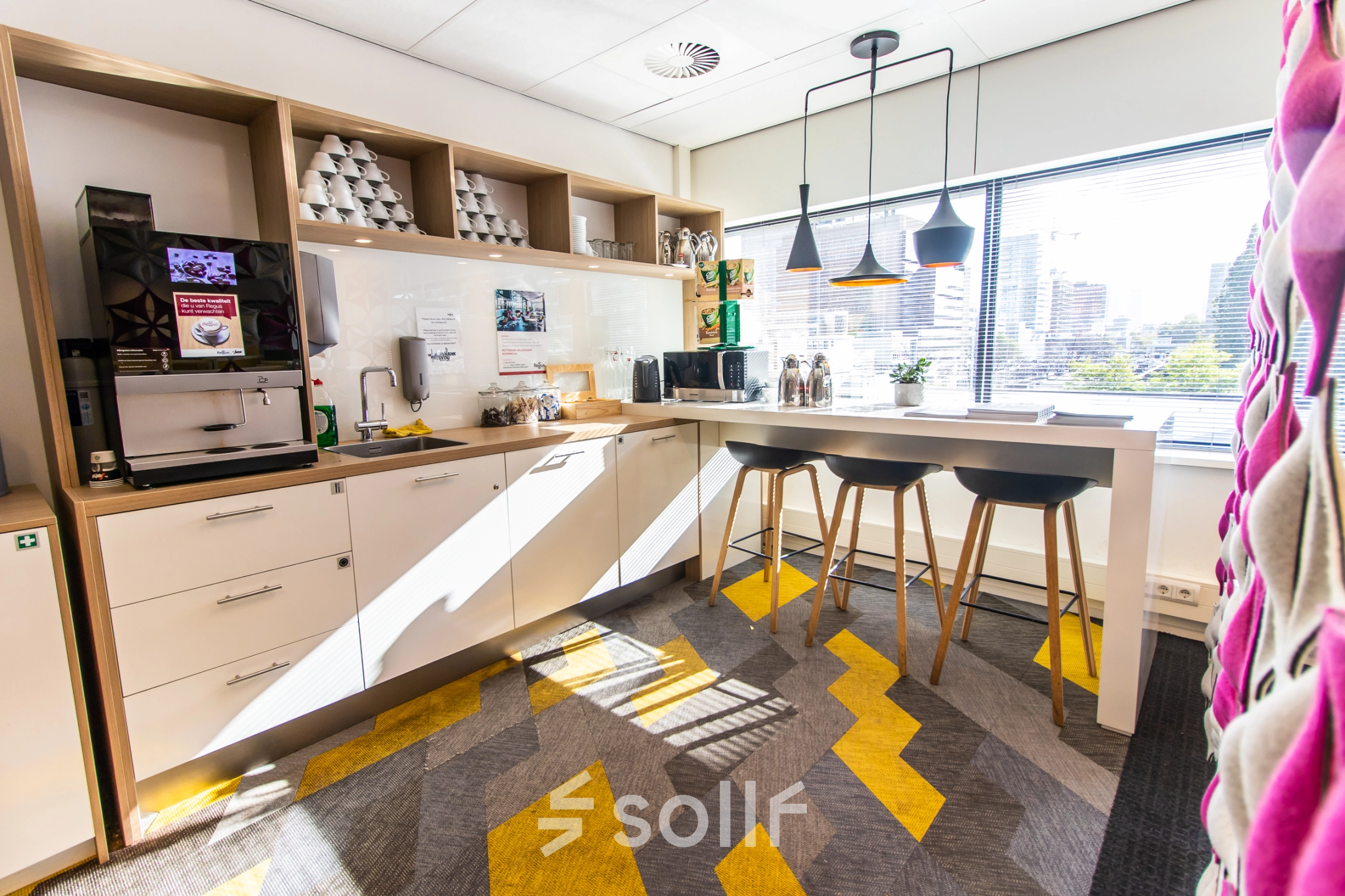 Bright and modern pantry at Weena-Zuid 130, Rotterdam Central Station, featuring a coffee machine, bar stools, and ample storage. Ideal spot in office space rental.