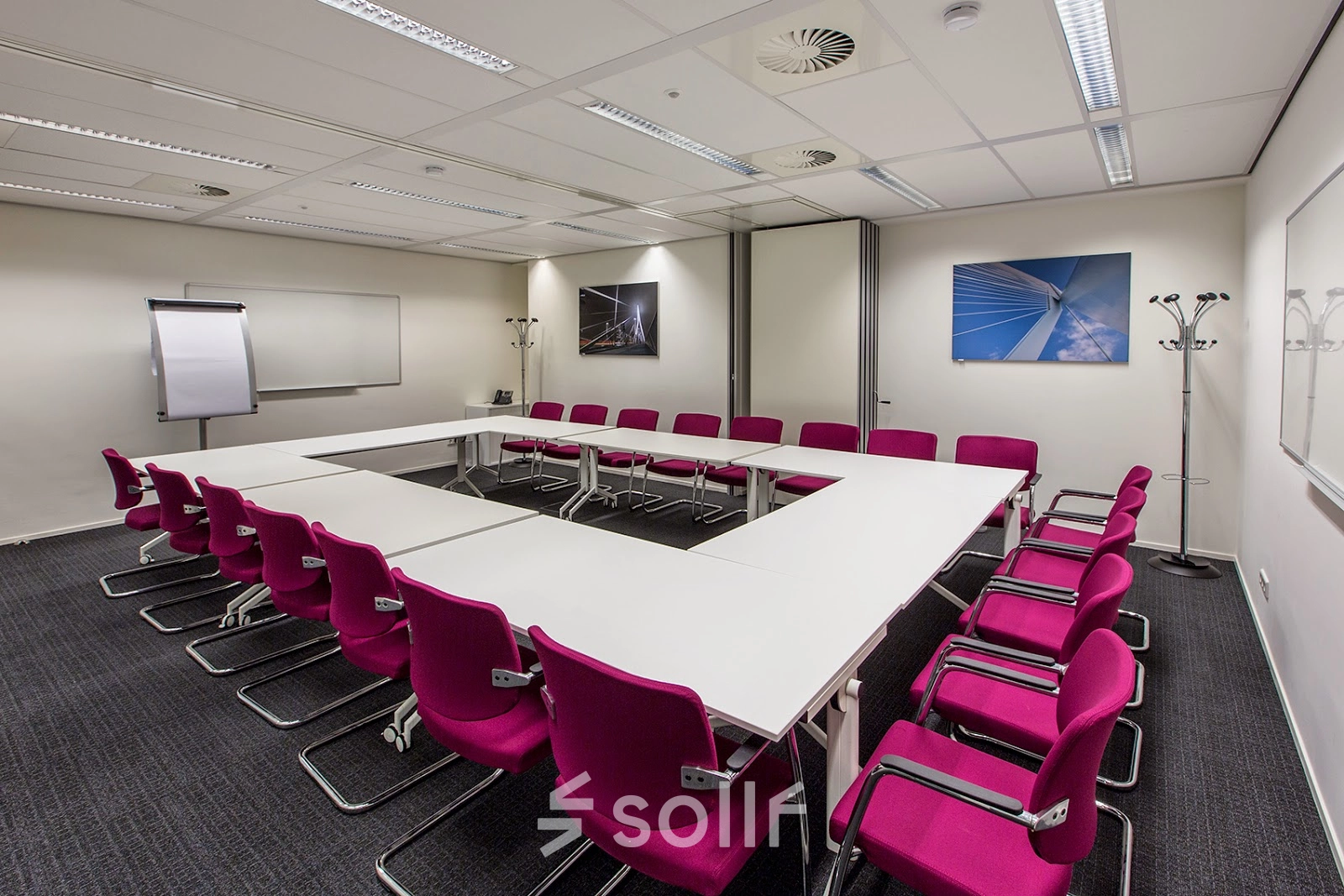 A furnished meeting room with a large U-shaped table and red chairs, perfect for office space rental at Weena-Zuid 130, Rotterdam Central Station.