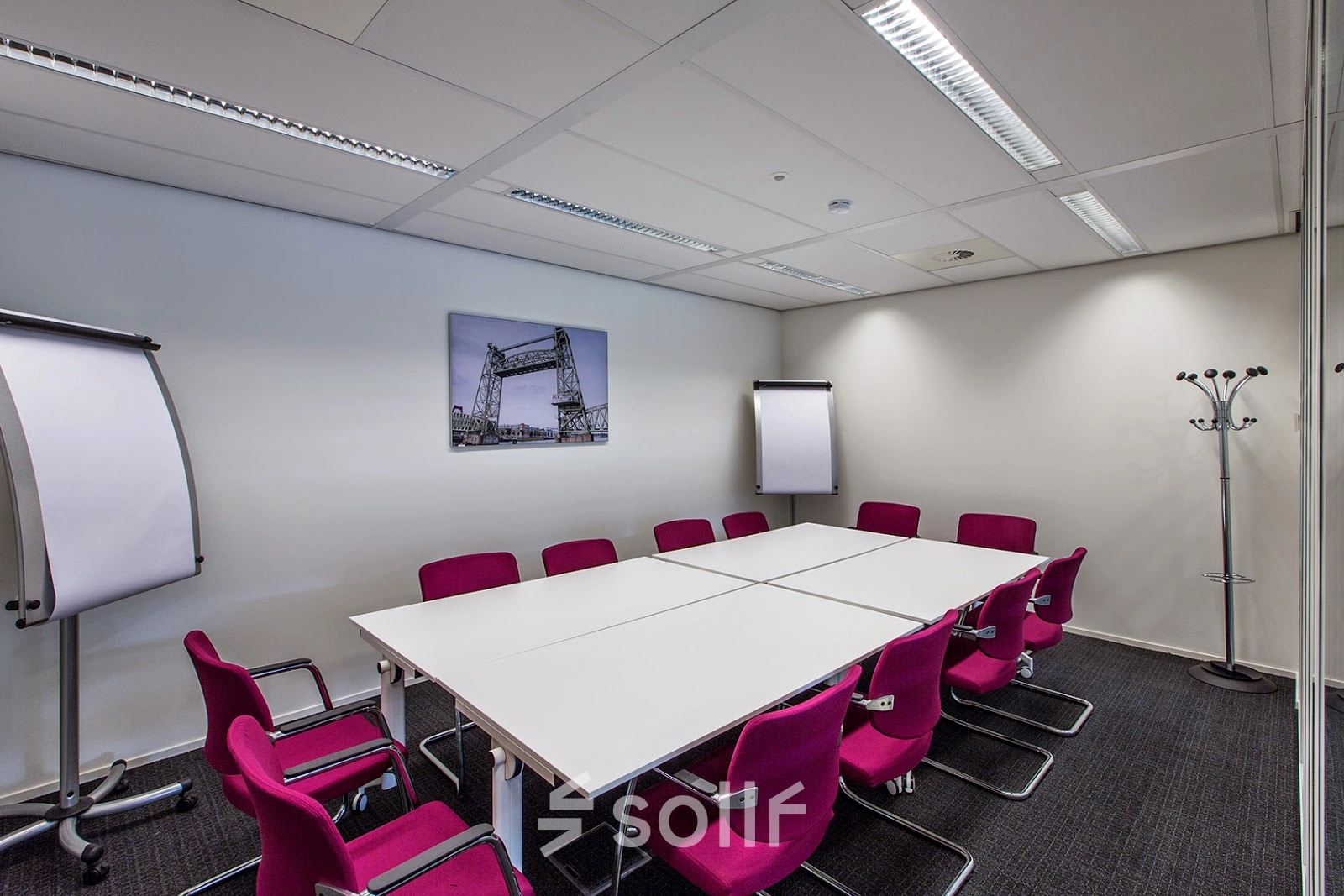 Furnished conference room at Weena-Zuid 130, Rotterdam Central Station, available for office space rental with magenta chairs and white tables.