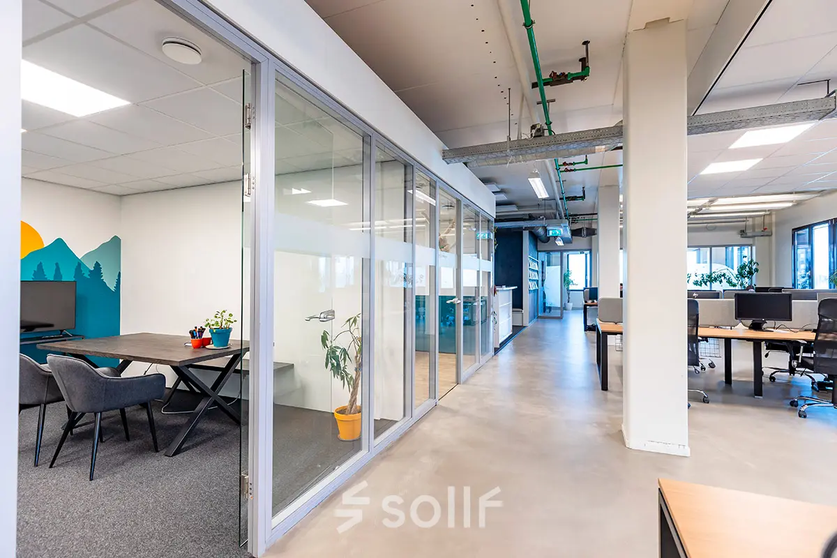 Modern office space at Kratonkade 7-27, featuring clear partitions, lounge chairs, and workstations, ideal for office space rental in Rotterdam Delfshaven.