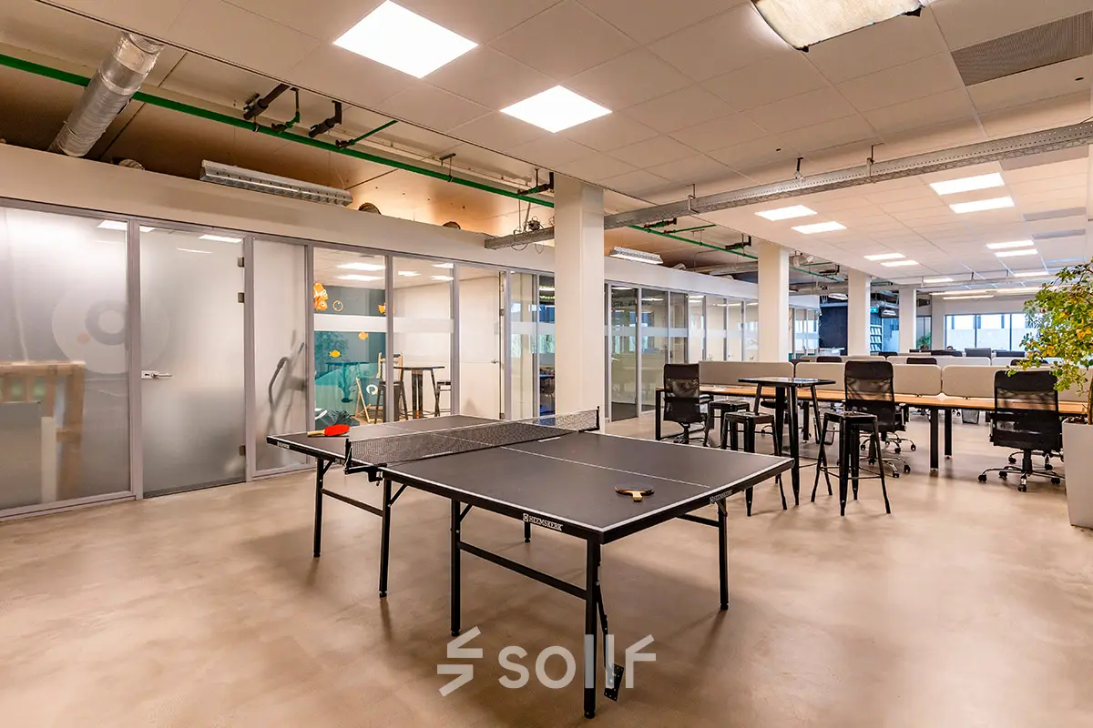 Interior view of a furnished office space featuring a ping pong table and desks at Kratonkade 7-27, Rotterdam Delfshaven, ideal for office space rental.