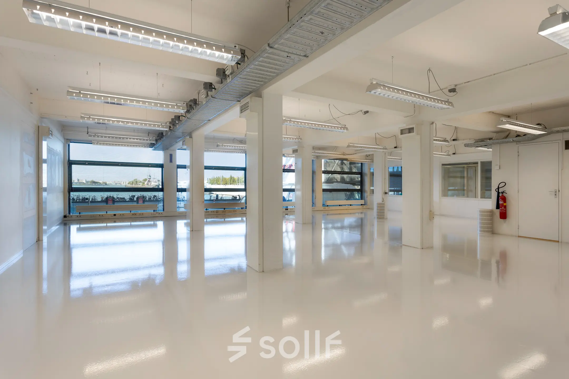 Interior view of a spacious, light-filled office at Lloydstraat 21 B, Rotterdam Delfshaven, available for office space rental. Large windows provide ample natural light.