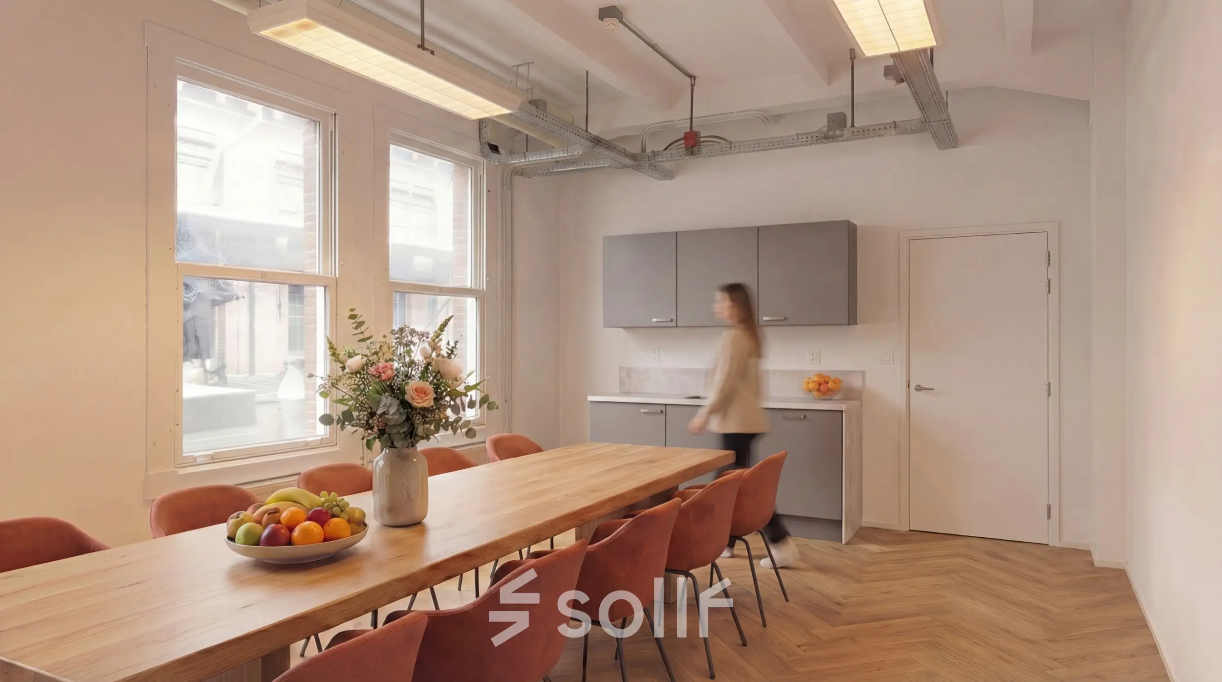 Bright office space at Lloydstraat 5 in Rotterdam Delfshaven featuring a long table, chairs, and a kitchenette.