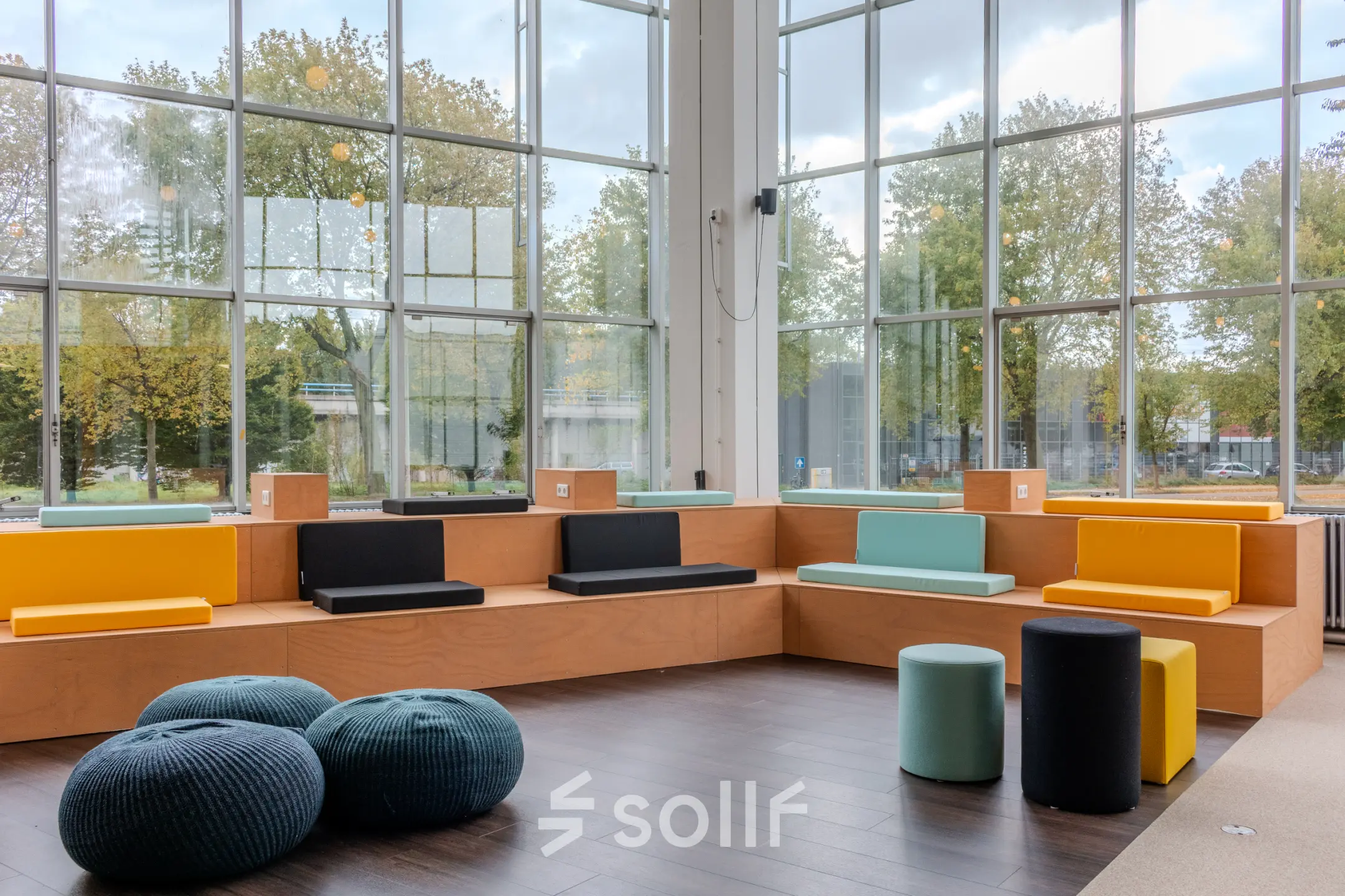 Bright, modern office space with colorful seating and large windows at Van Nelleweg 1 in Rotterdam Delfshaven available for rent.