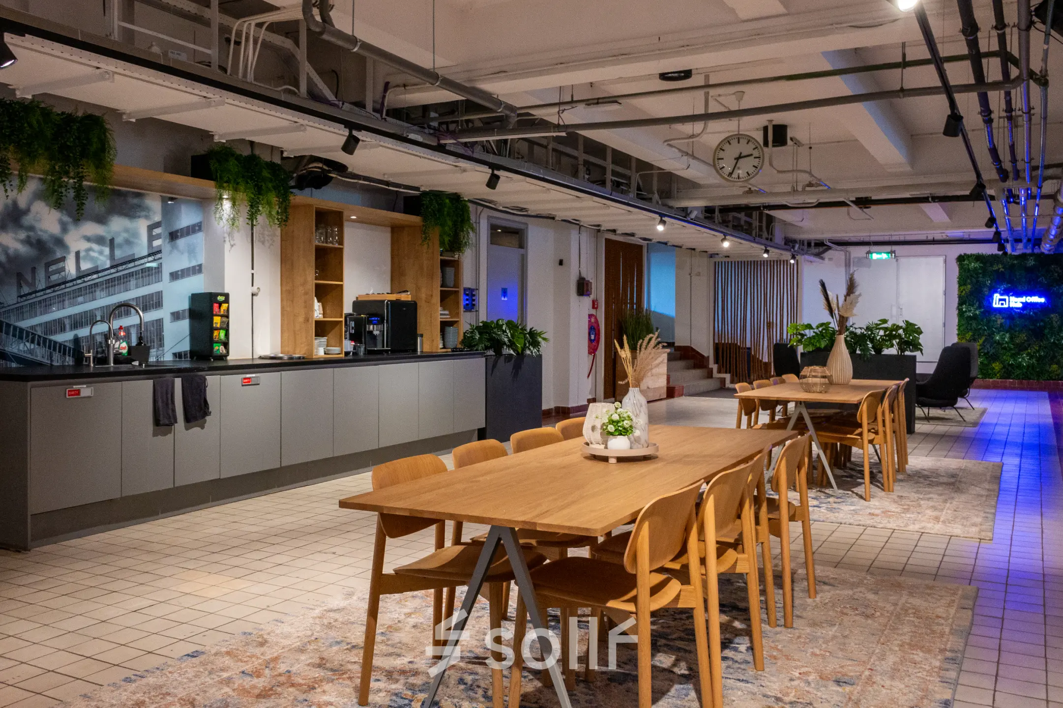Spacious office interior at Van Nelleweg 1, Rotterdam Delfshaven, featuring modern wooden tables, chairs, and a coffee area for office space rental.