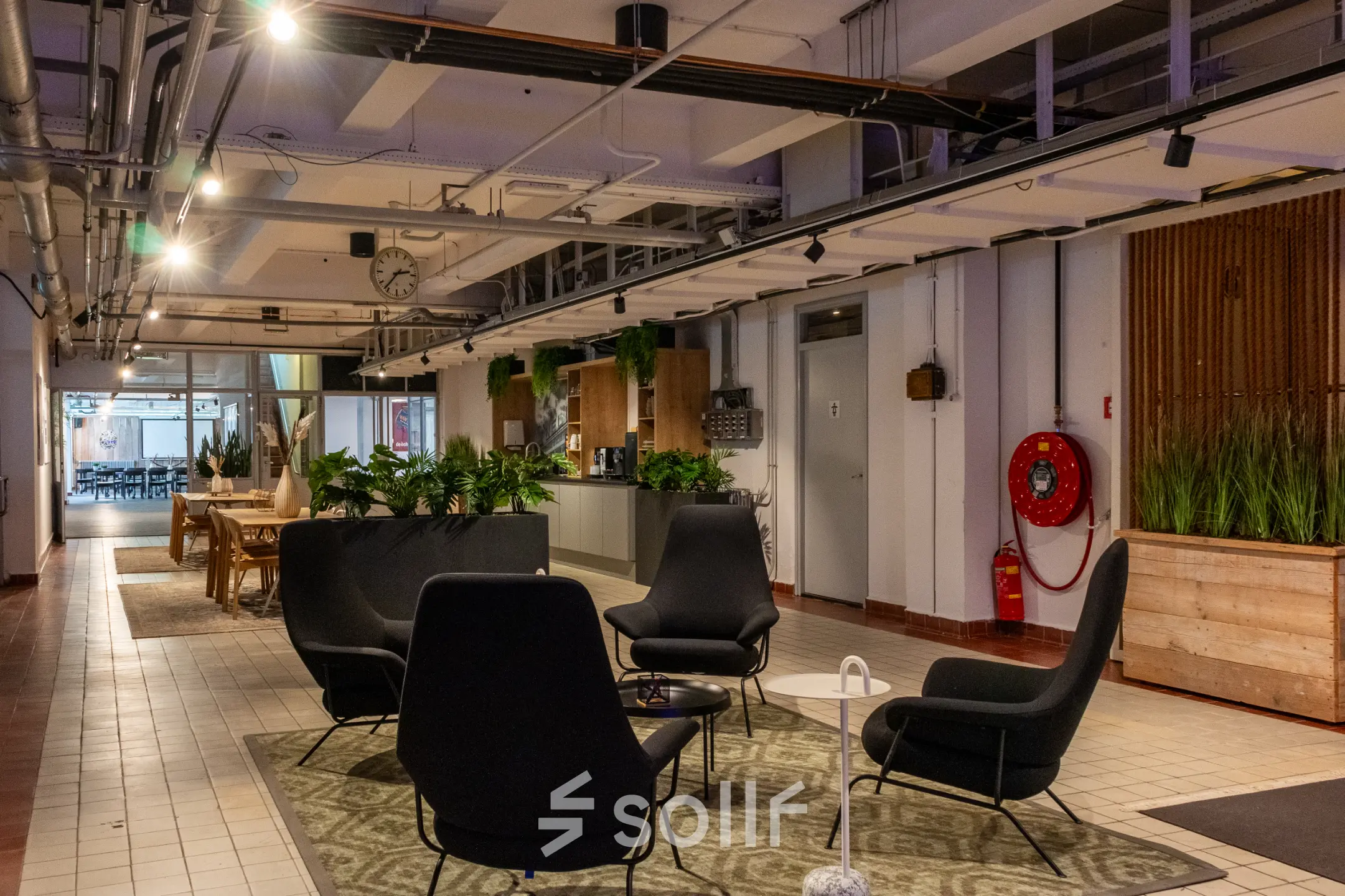 Furnished office space at Van Nelleweg 1, Rotterdam Delfshaven with seating arrangement, greenery and tables, ideal for office space rental.