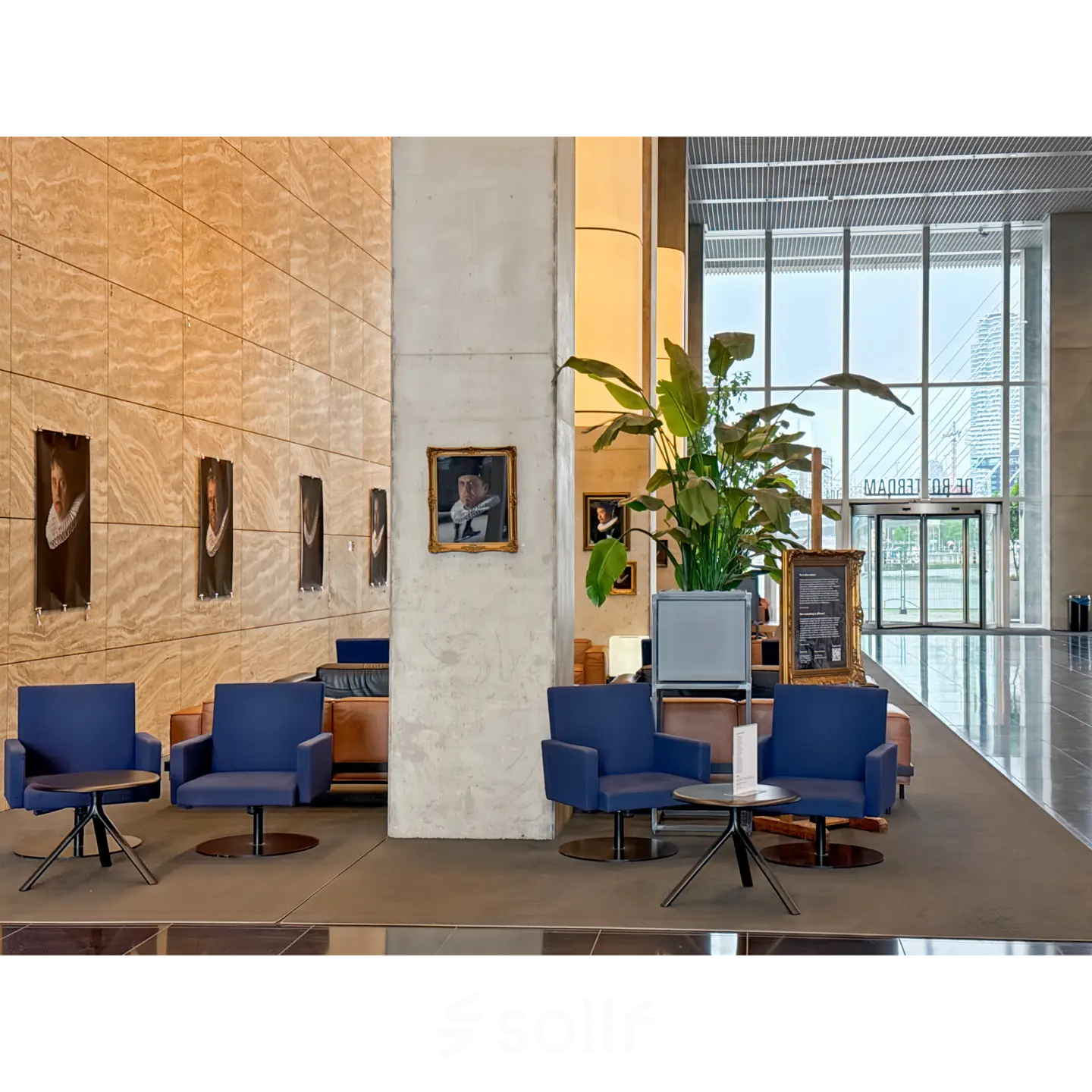 Modern office space at Wilhelminakade 173, Rotterdam Kop van Zuid, featuring stylish seating and decor for rent. Large plant adds a fresh touch to the open lobby area.