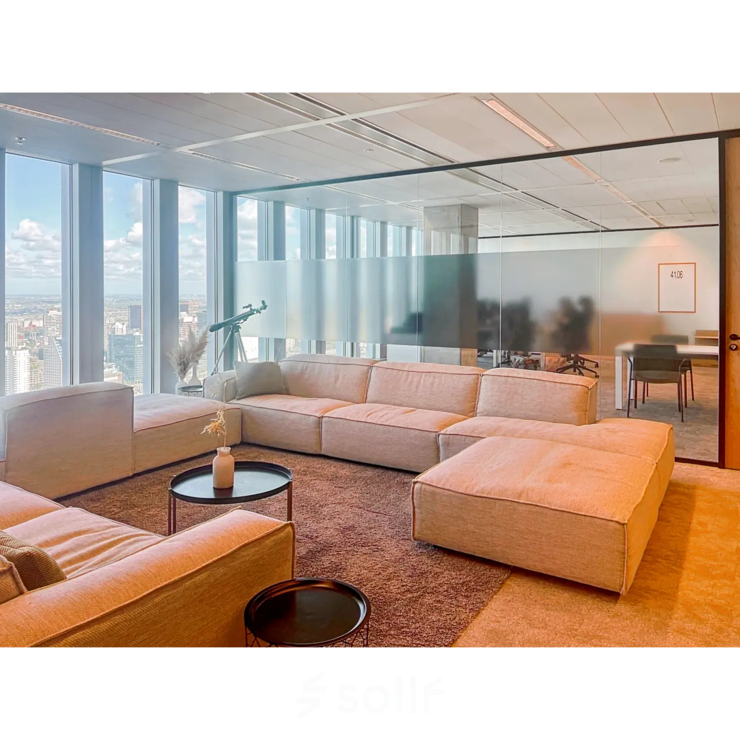 Spacious office lounge with comfortable seating and large windows offering a view of Rotterdam. Ideal for relaxing in a rented office space.