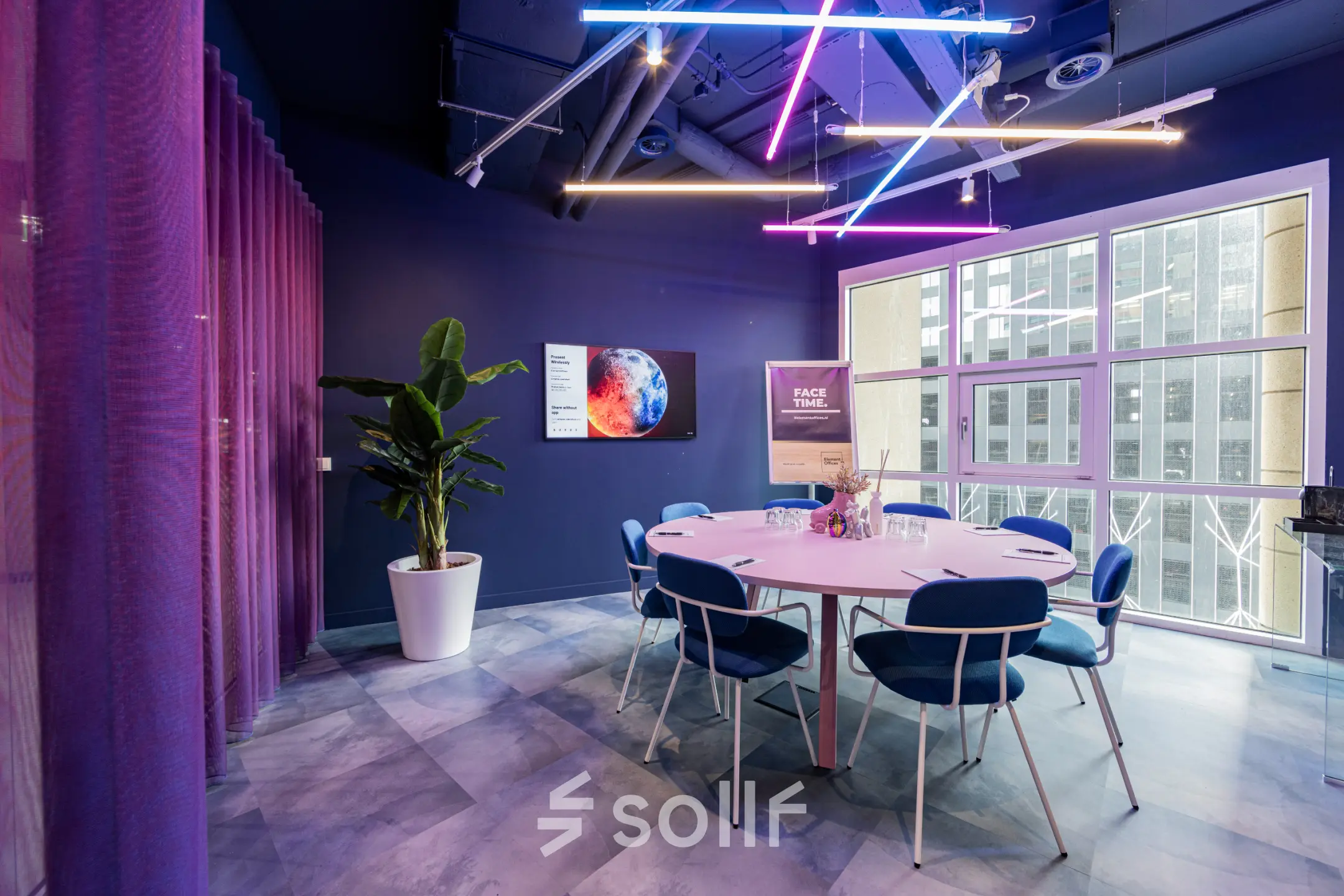 Modern furnished office space rental at Wilhelminaplein 1-40, Rotterdam Kop van Zuid, featuring vibrant lighting and a round table with chairs.