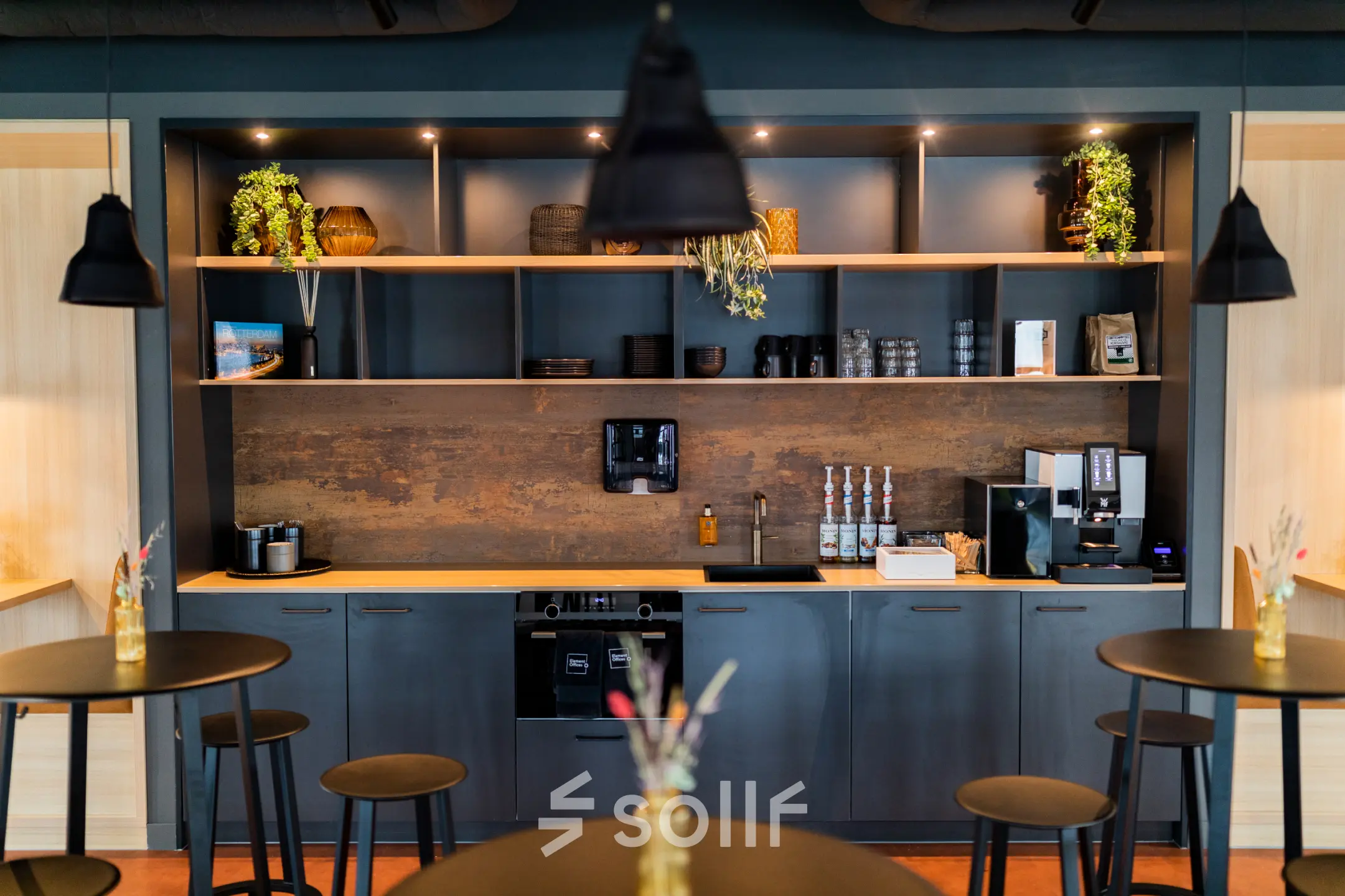 Furnished office space at Wilhelminaplein 1-40 in Rotterdam Kop van Zuid features a modern pantry area with sleek shelves, coffee machines, and stylish decor—ideal for a seamless office space rental experience.